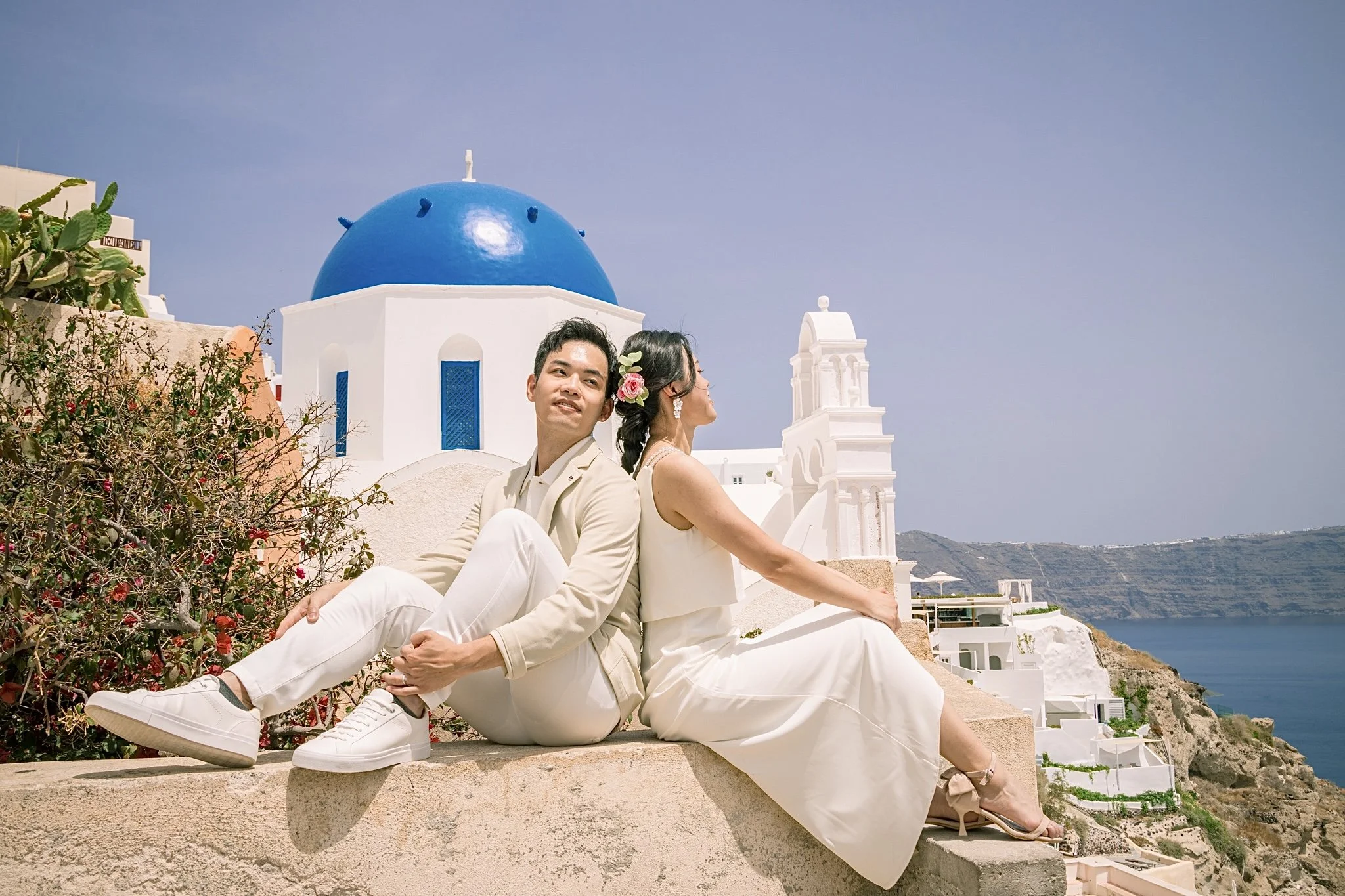 Captivating flying dress photography in Santorini with dramatic cliffs, azure domes, and professional editing.
