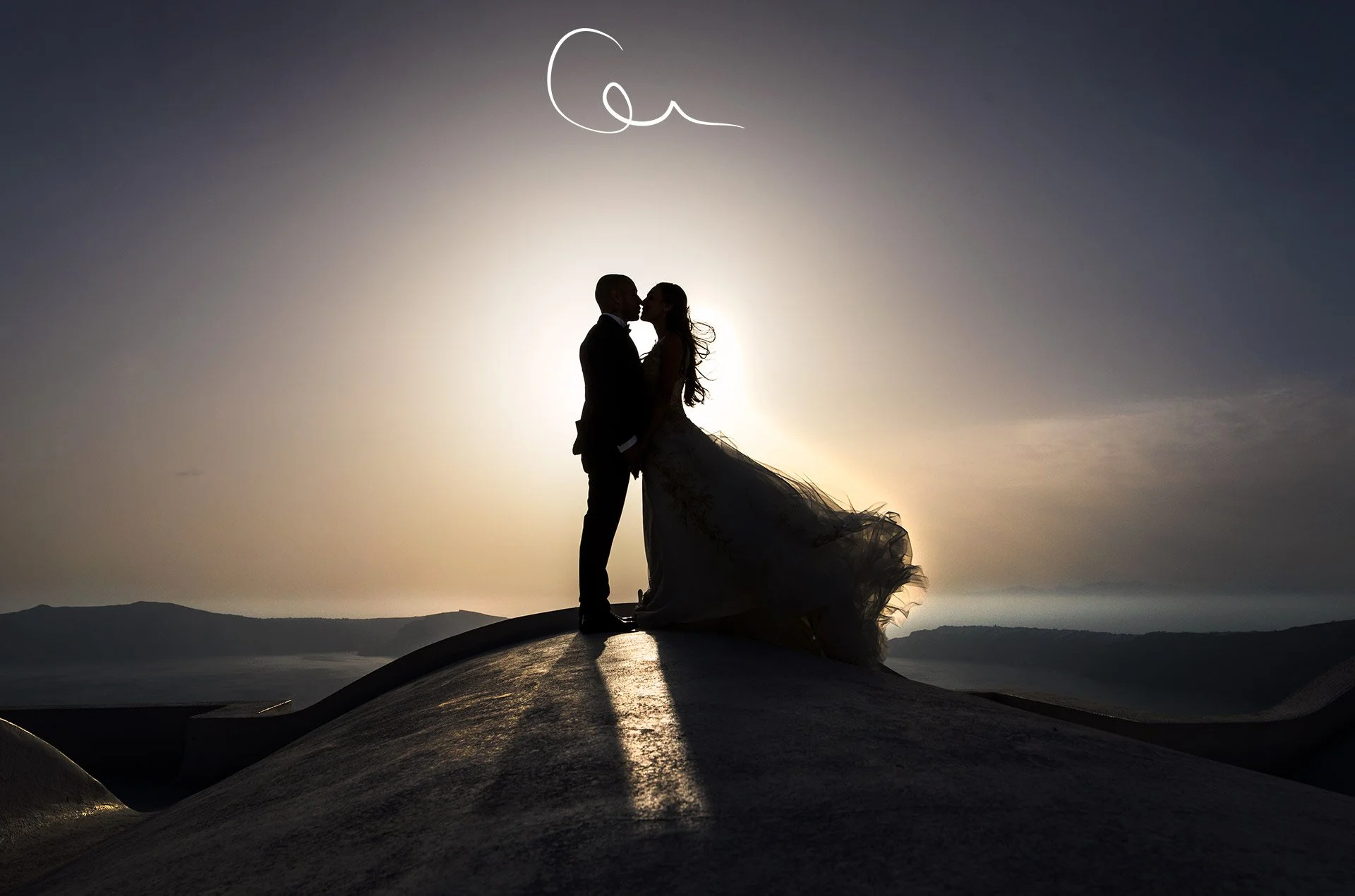 Striking bridal portraits on Perissa black sand beach, Santorini — volcanic shoreline contrasts with flowing white gown and dramatic late-afternoon golden hour light.