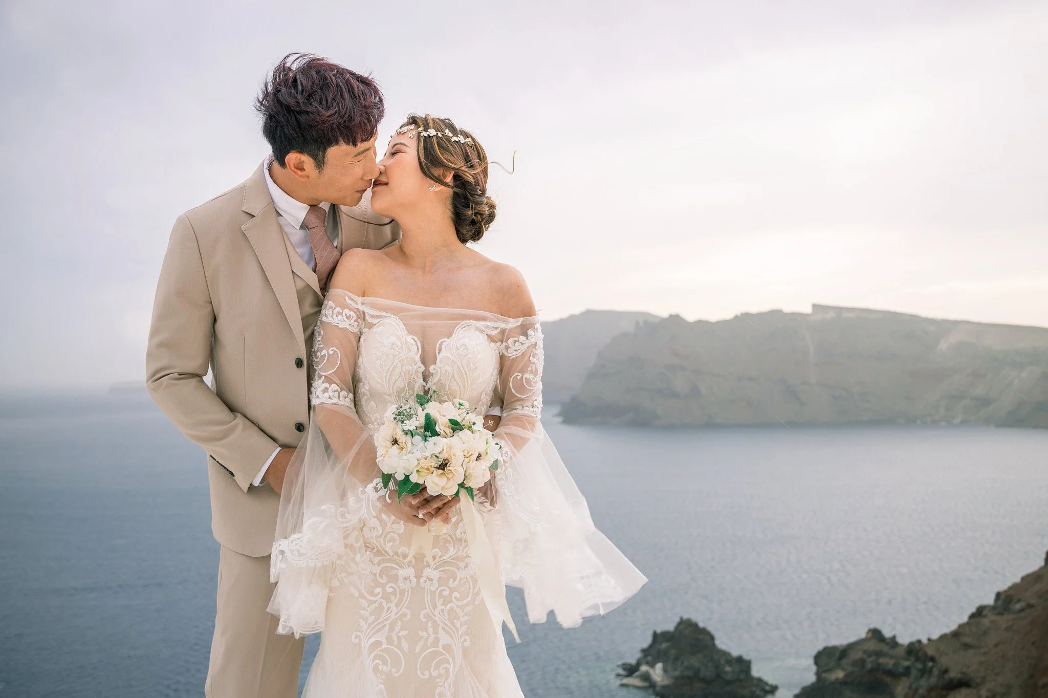 Lifestyle wedding portraits along the Fira cliff walk in Santorini, candid moments framed by Cycladic alleys and the Aegean Sea at dusk.