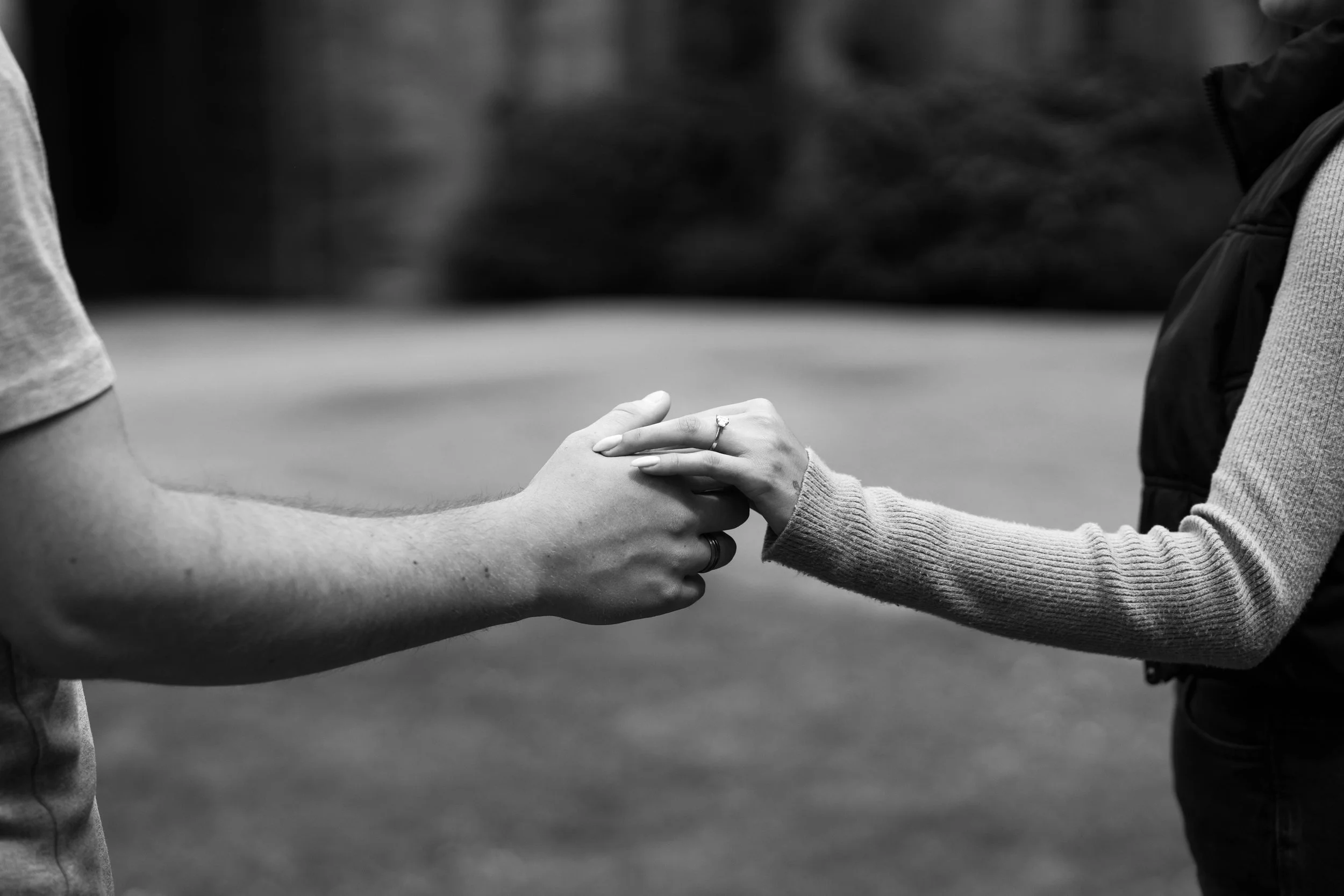 Two people holding hands, with one person's hand gently resting on top of the other's, in a tender gesture.