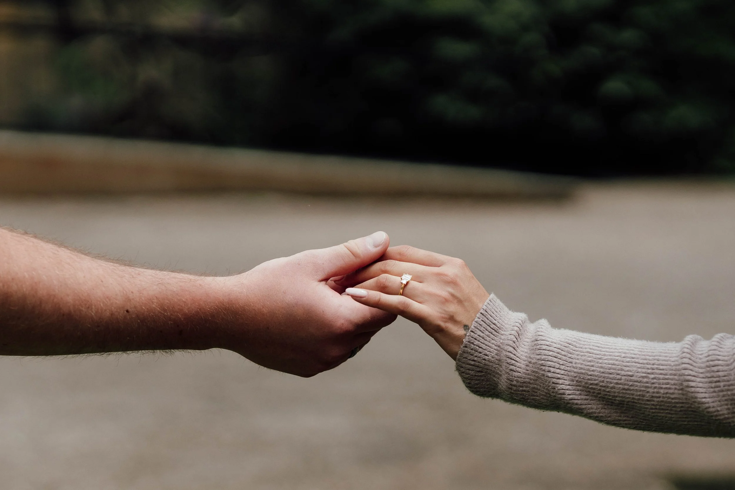 Two hands reaching for each other, with one hand wearing a diamond ring.