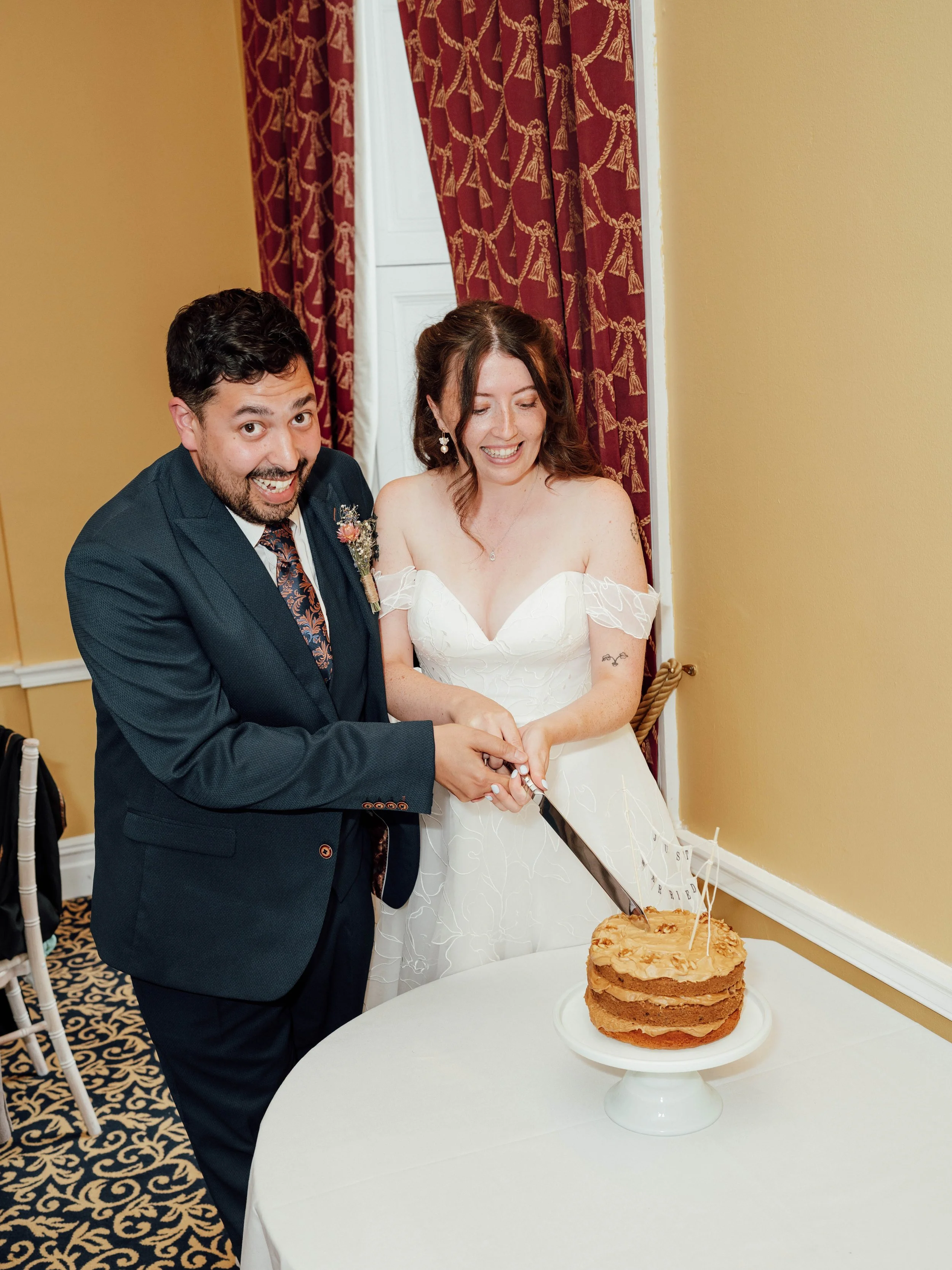 A bride and groom cutting a wedding cake together.