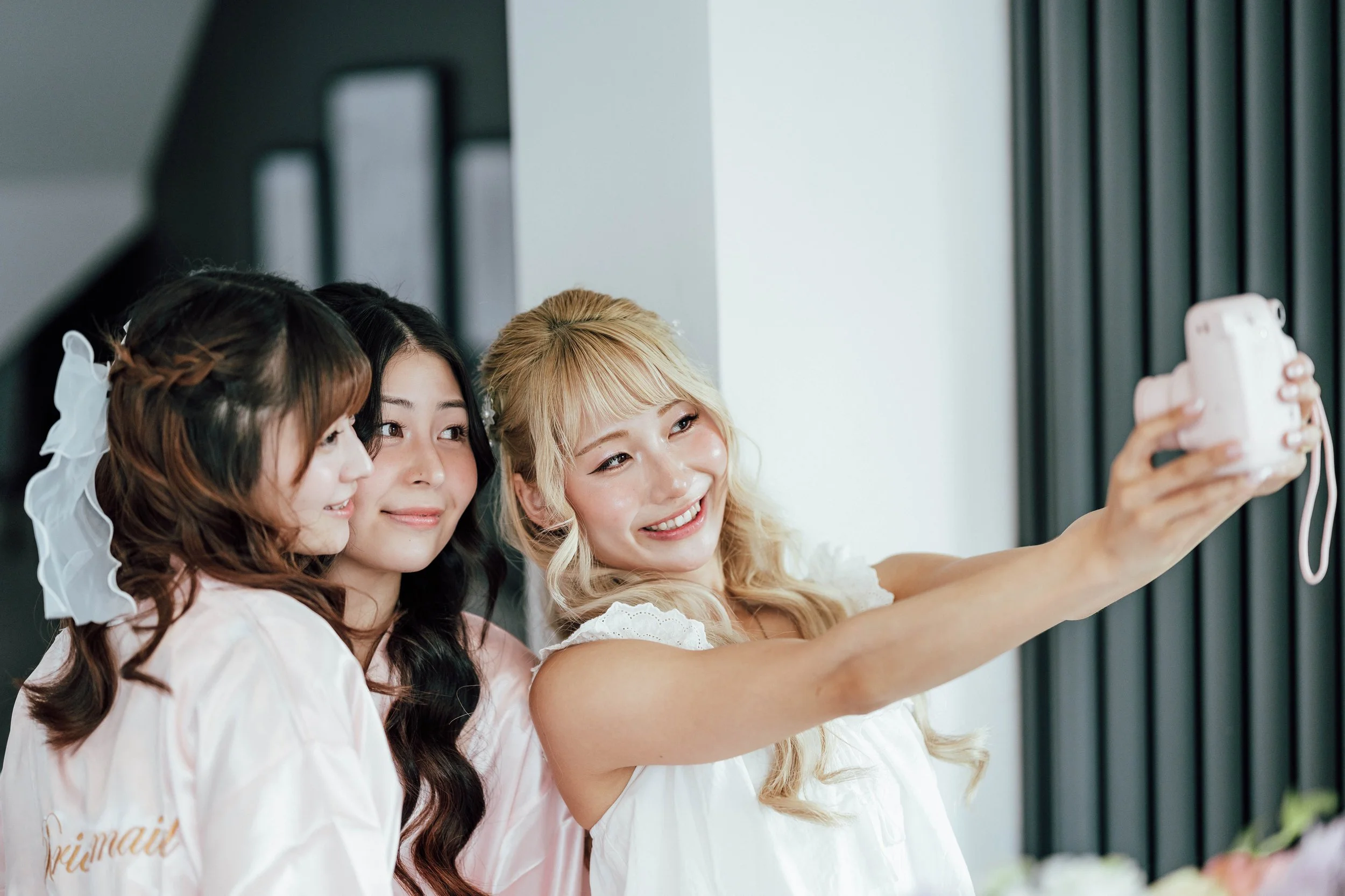 Three women taking a selfie together, smiling, indoors.