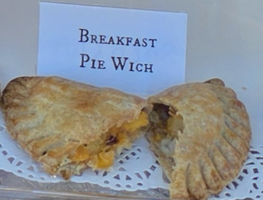 A delicious Pie Wich hand pie opened to show the ingredients, along with a card indicating the flavor.