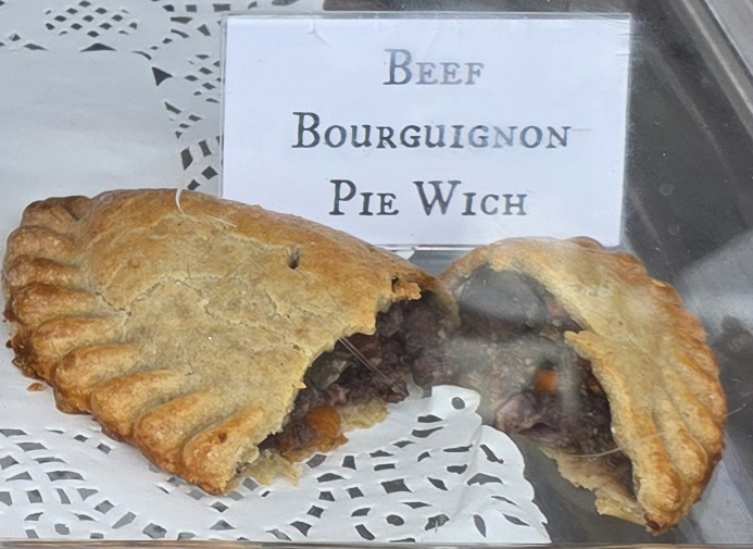 A delicious Pie Wich hand pie opened to show the ingredients, along with a card indicating the flavor.