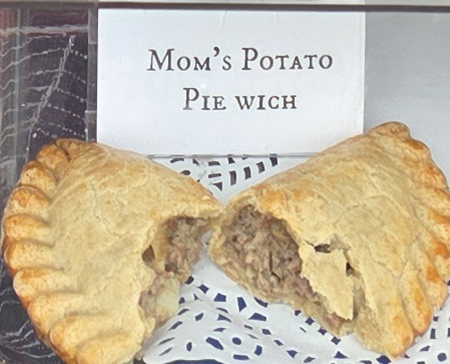 A delicious Pie Wich hand pie opened to show the ingredients, along with a card indicating the flavor.