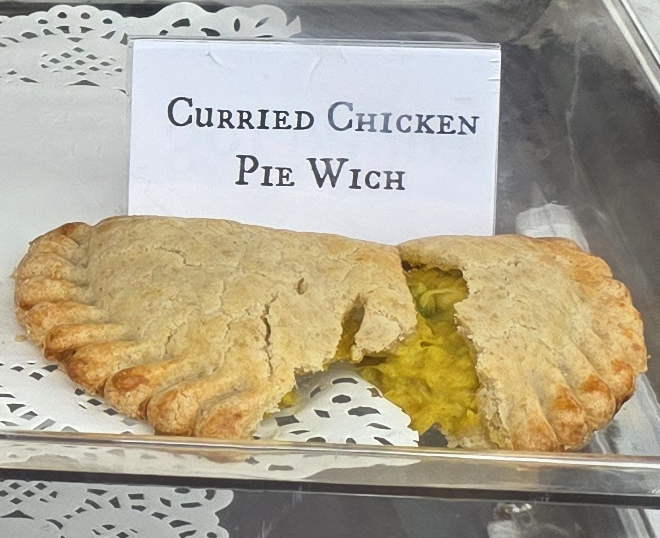 A delicious Pie Wich hand pie opened to show the ingredients, along with a card indicating the flavor.