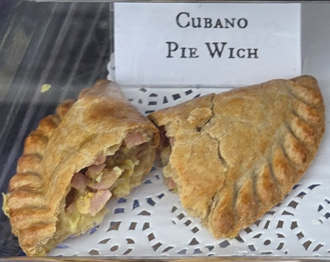 A delicious Pie Wich hand pie opened to show the ingredients, along with a card indicating the flavor.