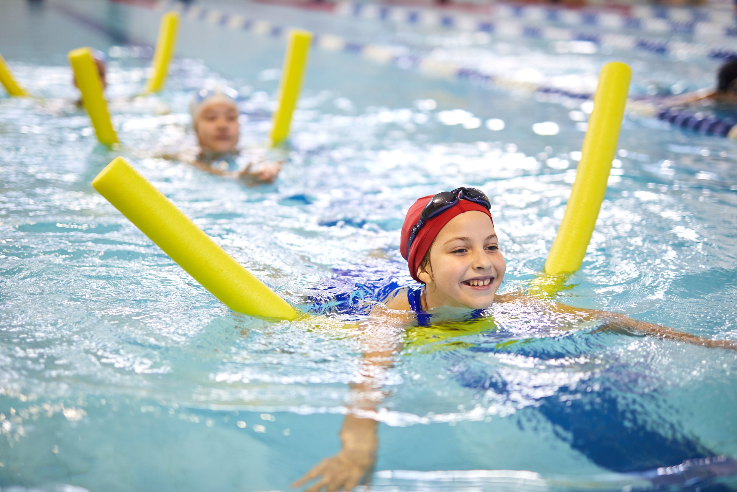 Child learning to swim with flotation noodles during a private swim lesson in the Greater Nashville area