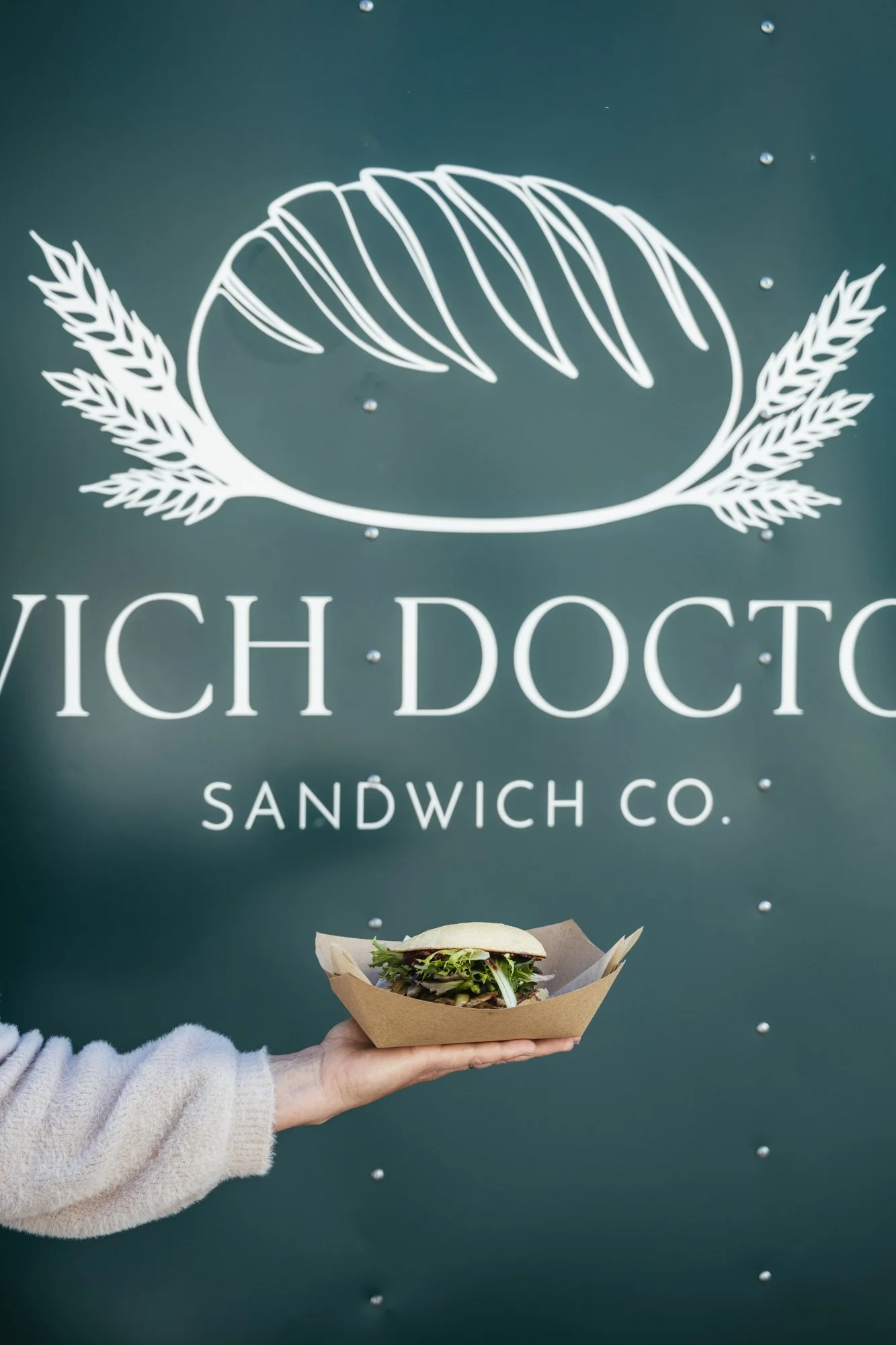 woman holding sandwich in front of food truck with wich doctor sandwich co