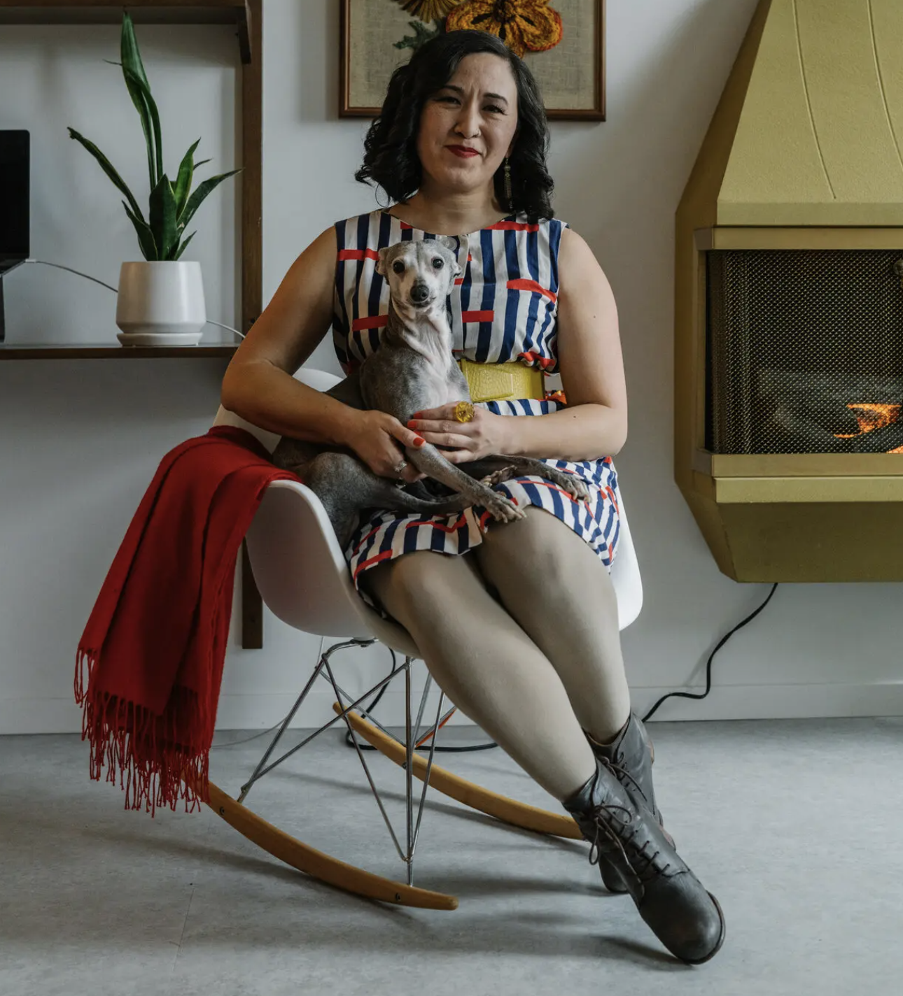 Woman sits on chair with dog in lap 