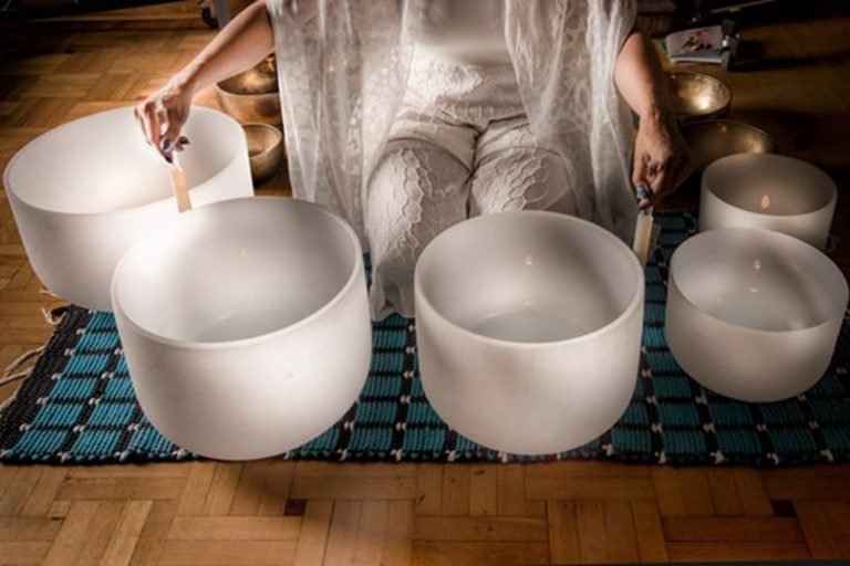 woman dressed in white surrounded by sound bowls