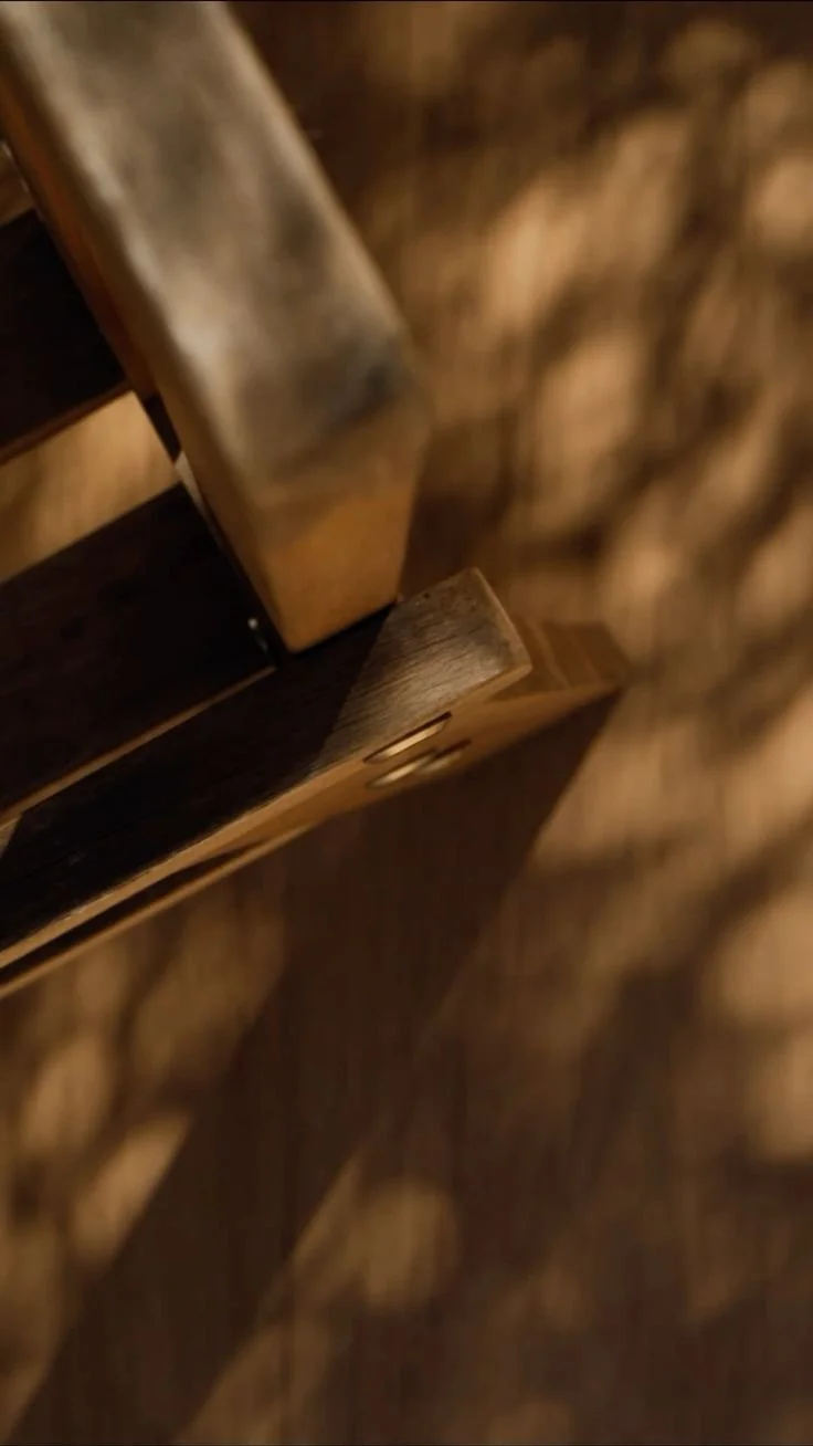 Close-up of a wooden chair with a visible shadow on a wooden floor.