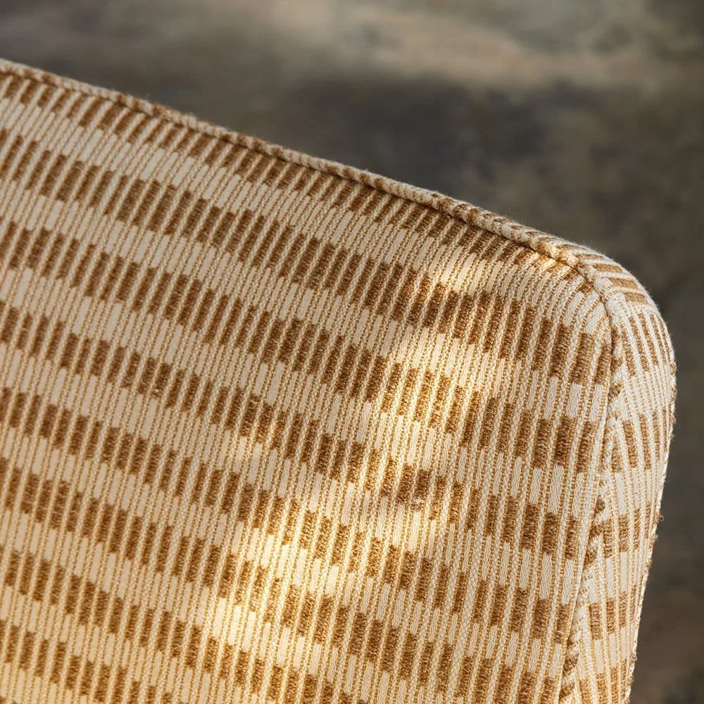 Close-up of a beige and brown striped upholstered chair backrest with a textured fabric.