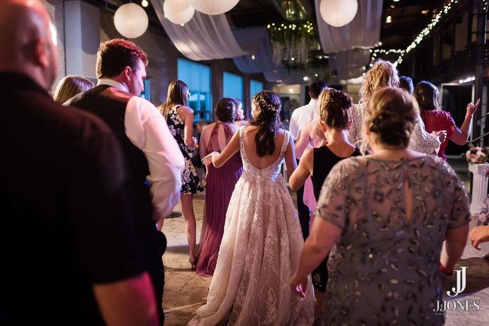 People dancing at a wedding reception with hanging lanterns and string lights.