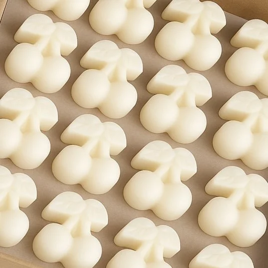 Creamy white cherry-shaped soy wax melts arranged in a kraft box.
