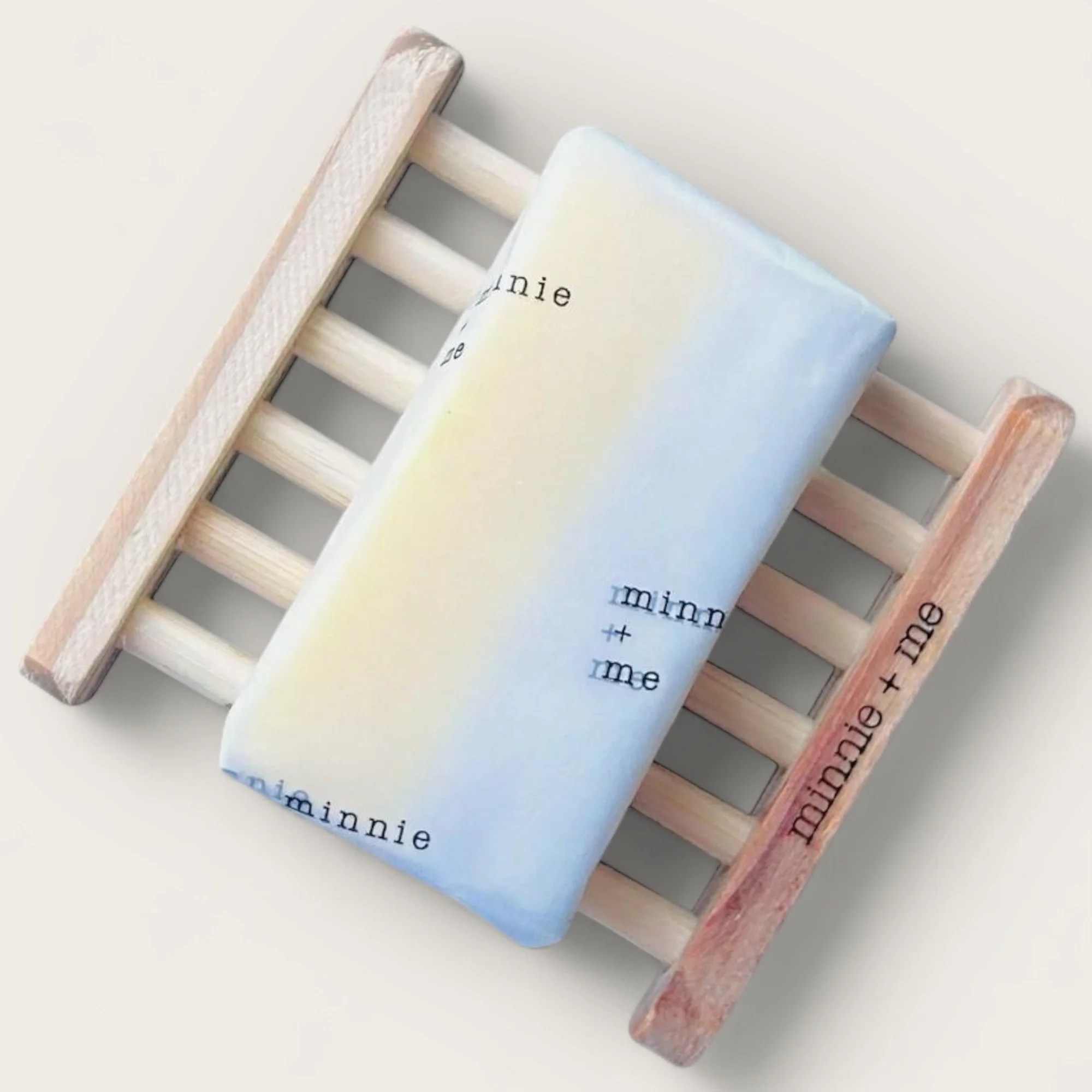 A pastel-colored soap with the words 'minnie' and 'me' pattern printed, resting on a small wooden pallet.