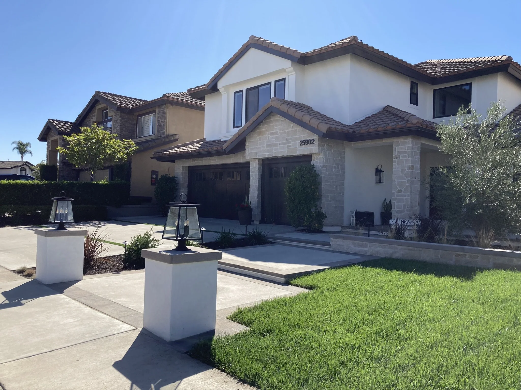 Front yard after. We added limestone veneer, in a rough cut, new paint, concrete with paver boarder and new planter walls. Wood garage doors were added to elevate the whole house. New lighting and plants to finish the upscale design. 