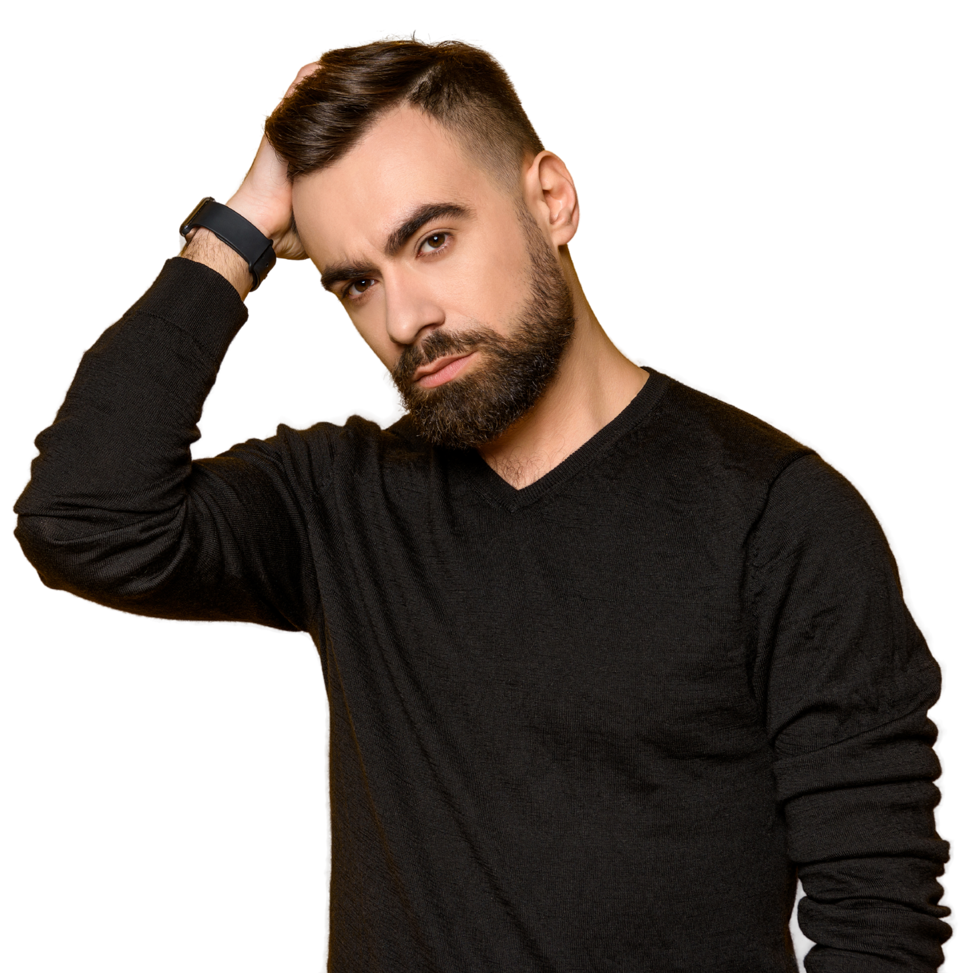 A young man with a beard and styled hair, wearing a black long-sleeve shirt, looks into the camera with a serious expression, touching his hair with one hand.