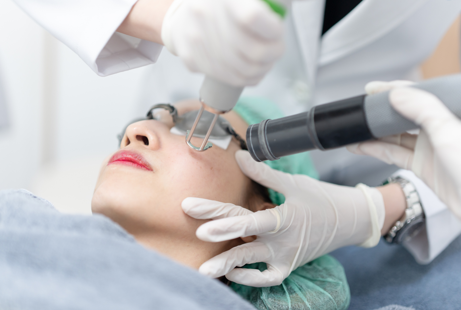 A woman undergoing a laser or dermatological treatment on her face by a medical professional in a clinical setting.