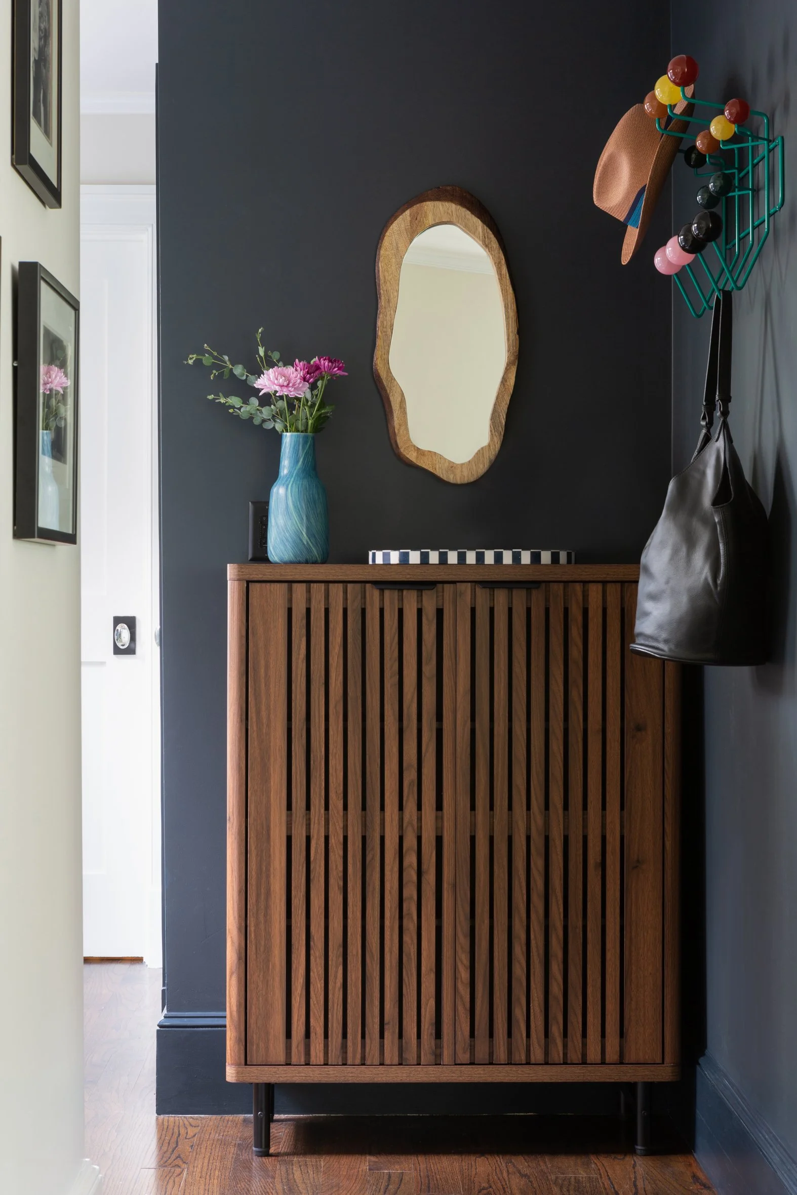An entryway with a shoe cabinet and organic mirror.