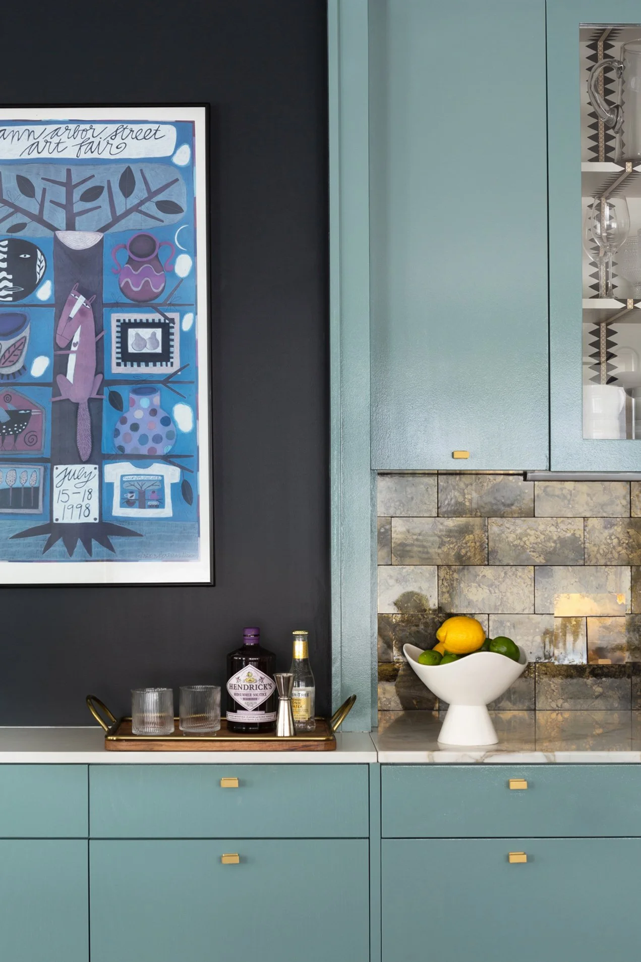 A vignette of a turquoise-painted custom bar with a fruit bowl.