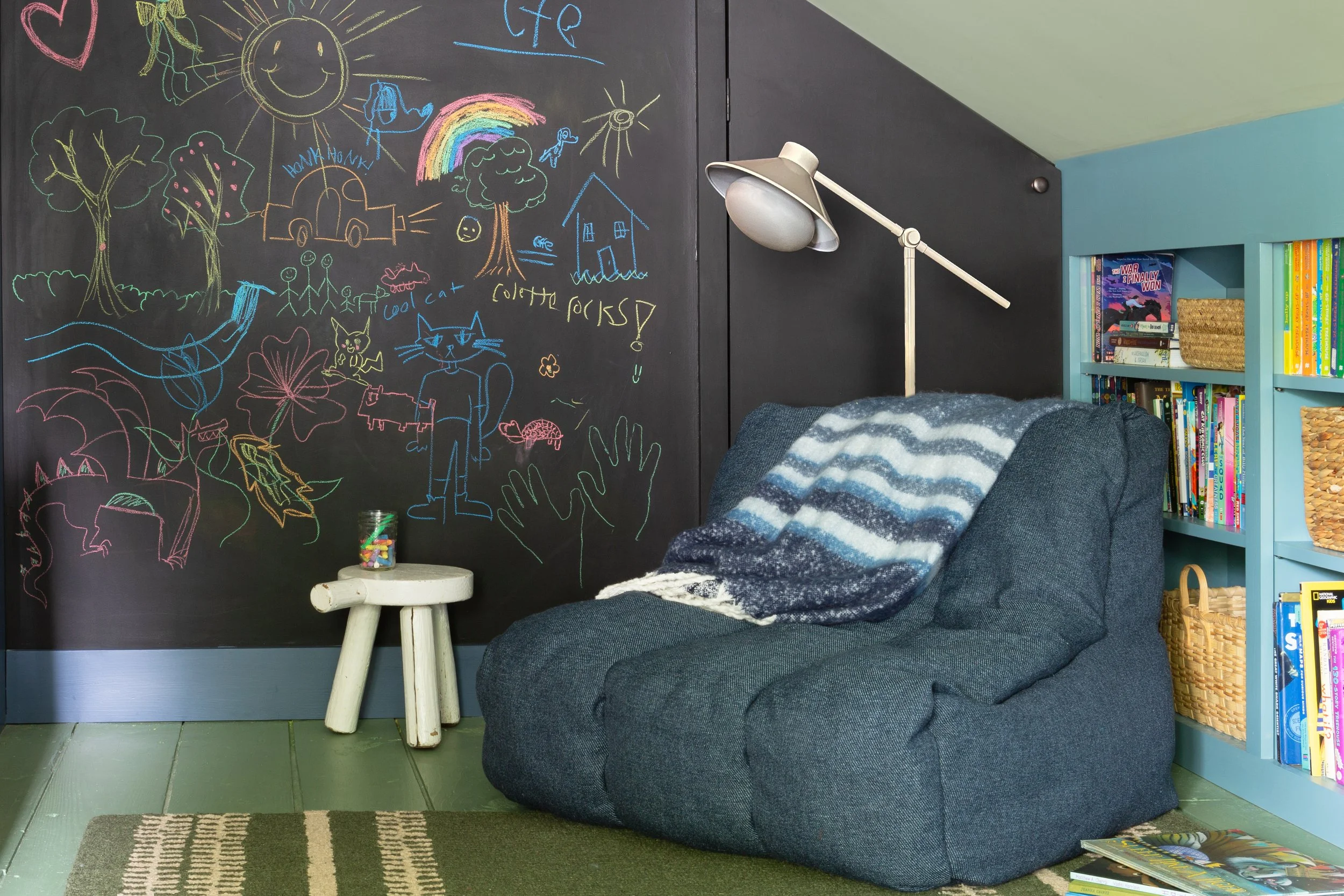 In an attic play room, a chalkboard wall sits behind a bean bag chair.