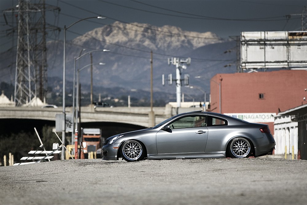 Silver car parked on street with mountain and industrial background
