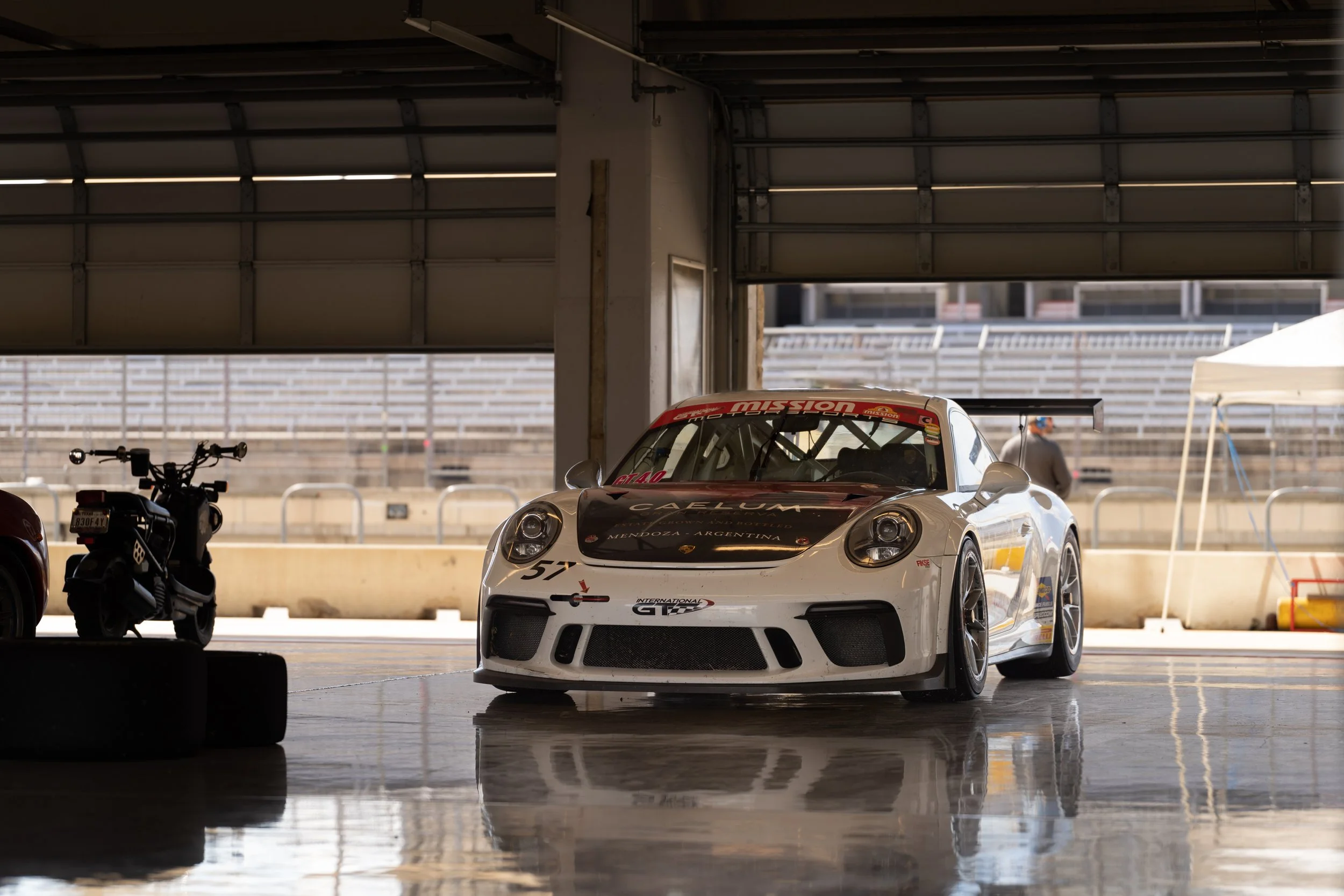 Porsche race car parked in garage at COTA for track event.