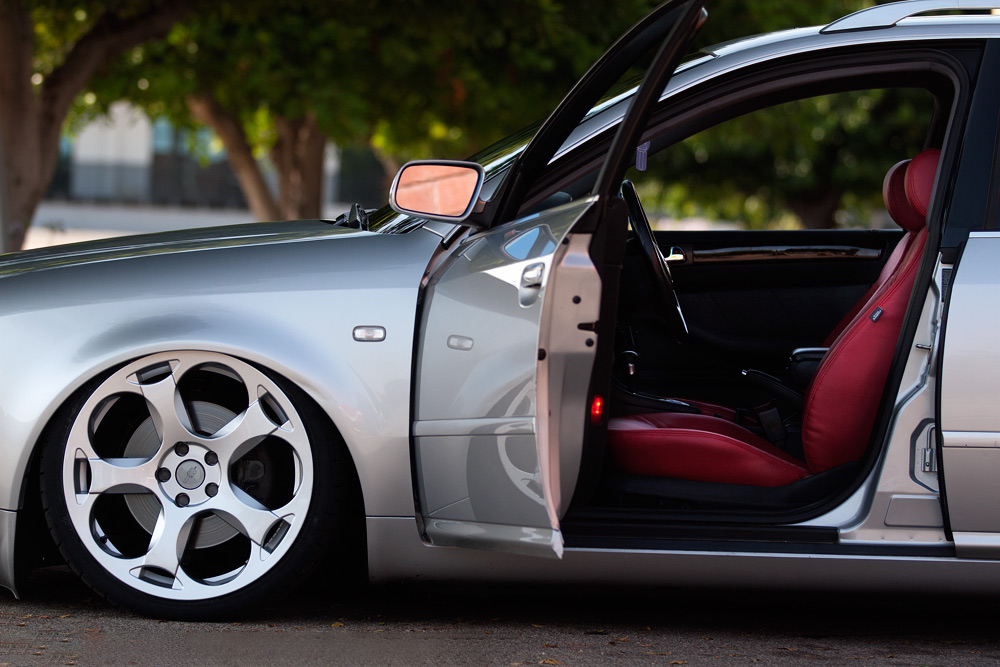 Silver car with red leather interior, open door, custom alloy wheels