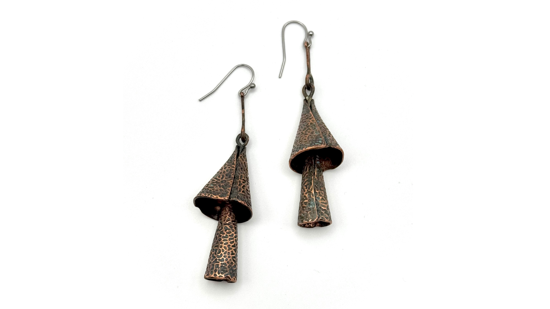 Pair of artisanal copper earrings with cone-shaped designs and textured surface on a white background.