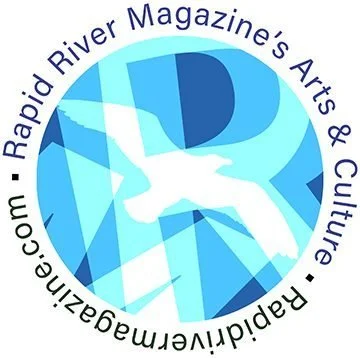 Circular logo with the text 'Rapid River Magazine's Arts & Culture' and a website URL, featuring shades of blue and abstract design elements.