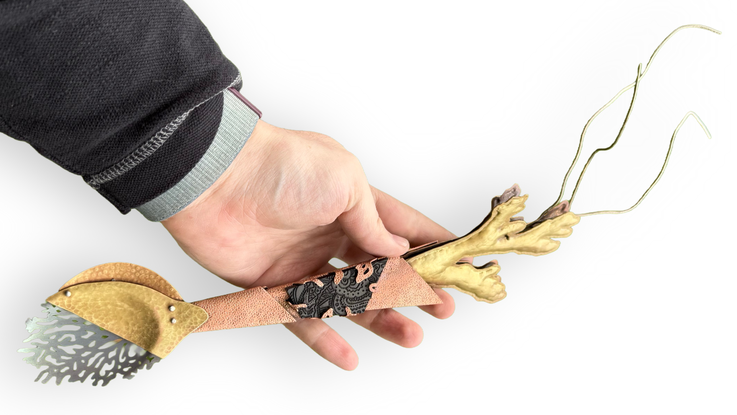CONSUMING THE TIDE. 2026. A sculptural exploration of human consumption and its devastating impact on global coral reefs, framed within the ironic structure of a spoon.

It is hand-pierced titanium, traditional chased-and-repoussé brass, and textured