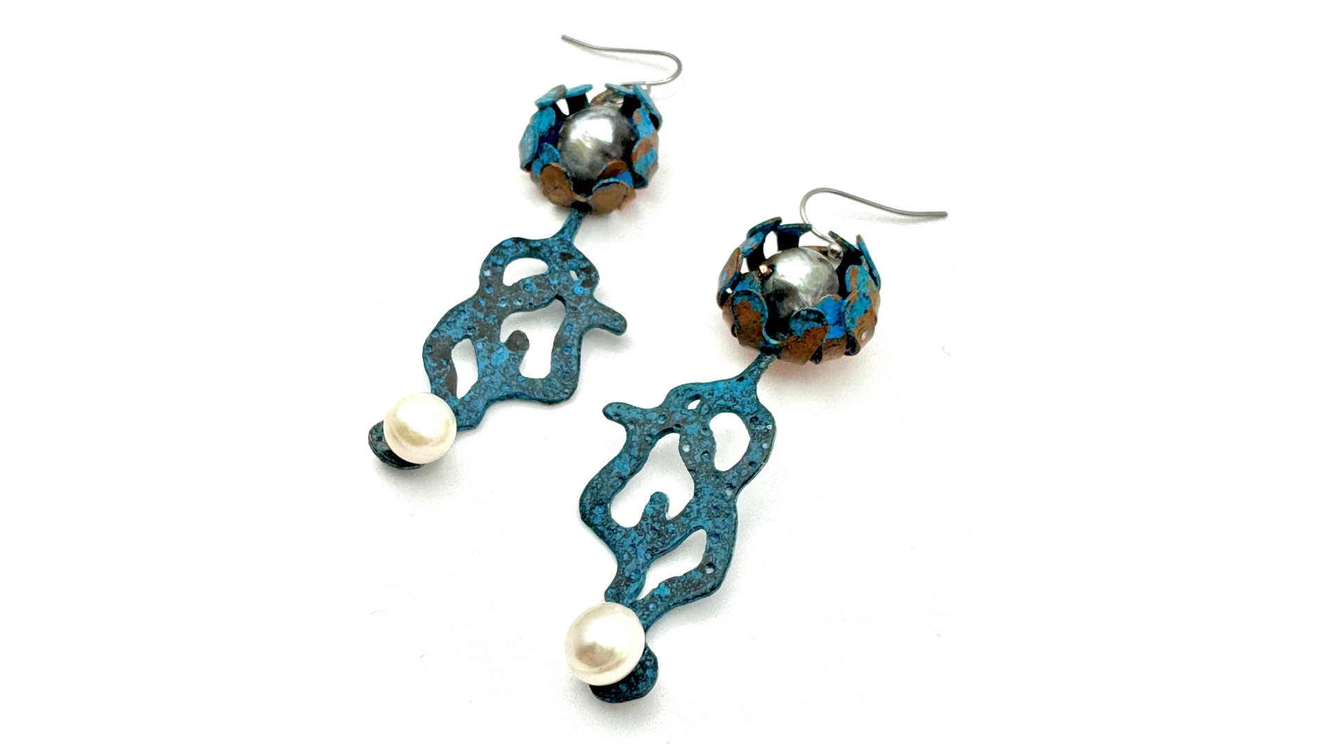 A pair of artistic earrings featuring textured blue metal shapes with white pearl accents and spherical decorative elements with a mix of blue, brown, and silver colors.