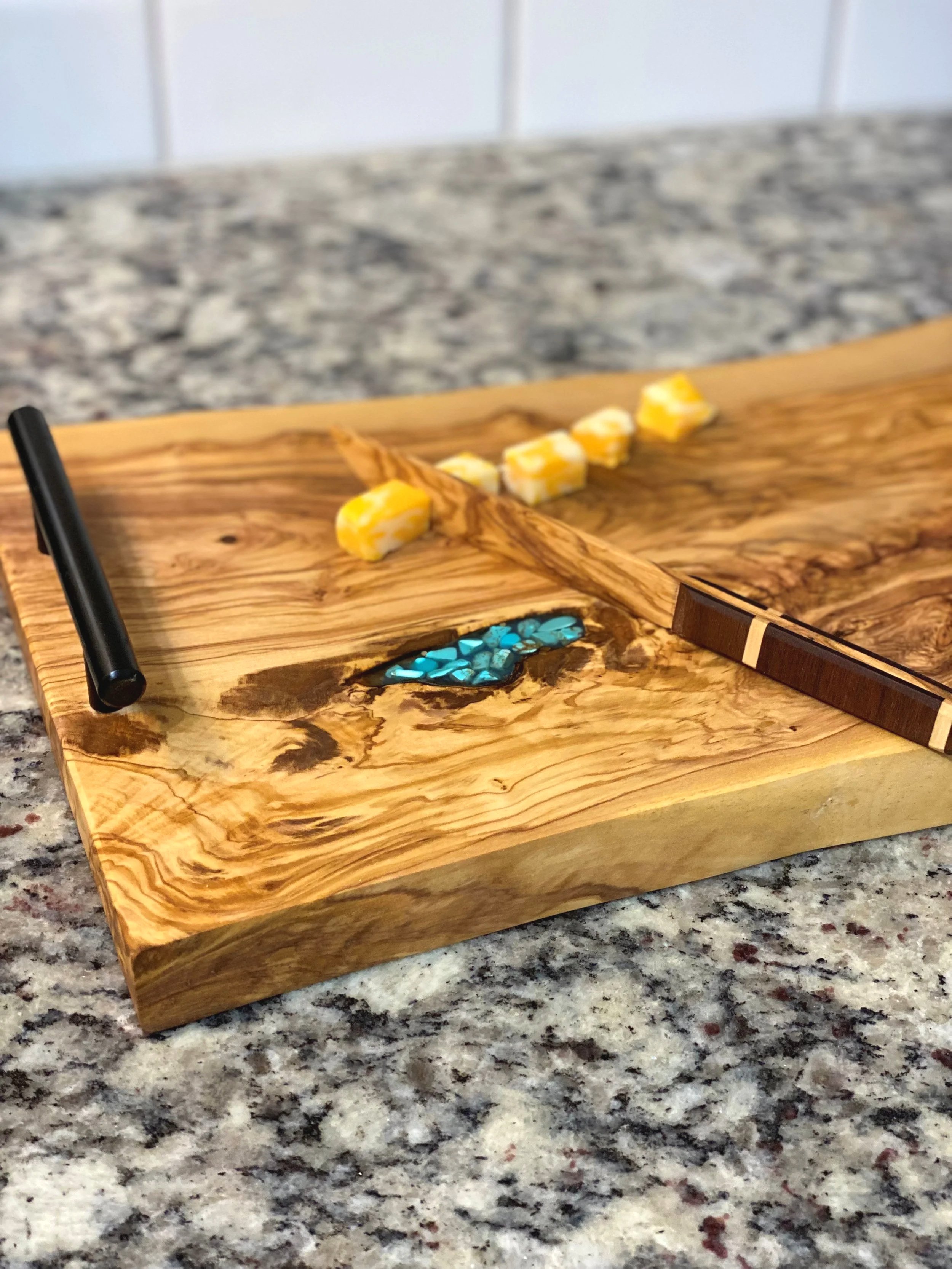 A wooden Olive wood tray with an Olive wood knife, placed on a speckled granite counter.