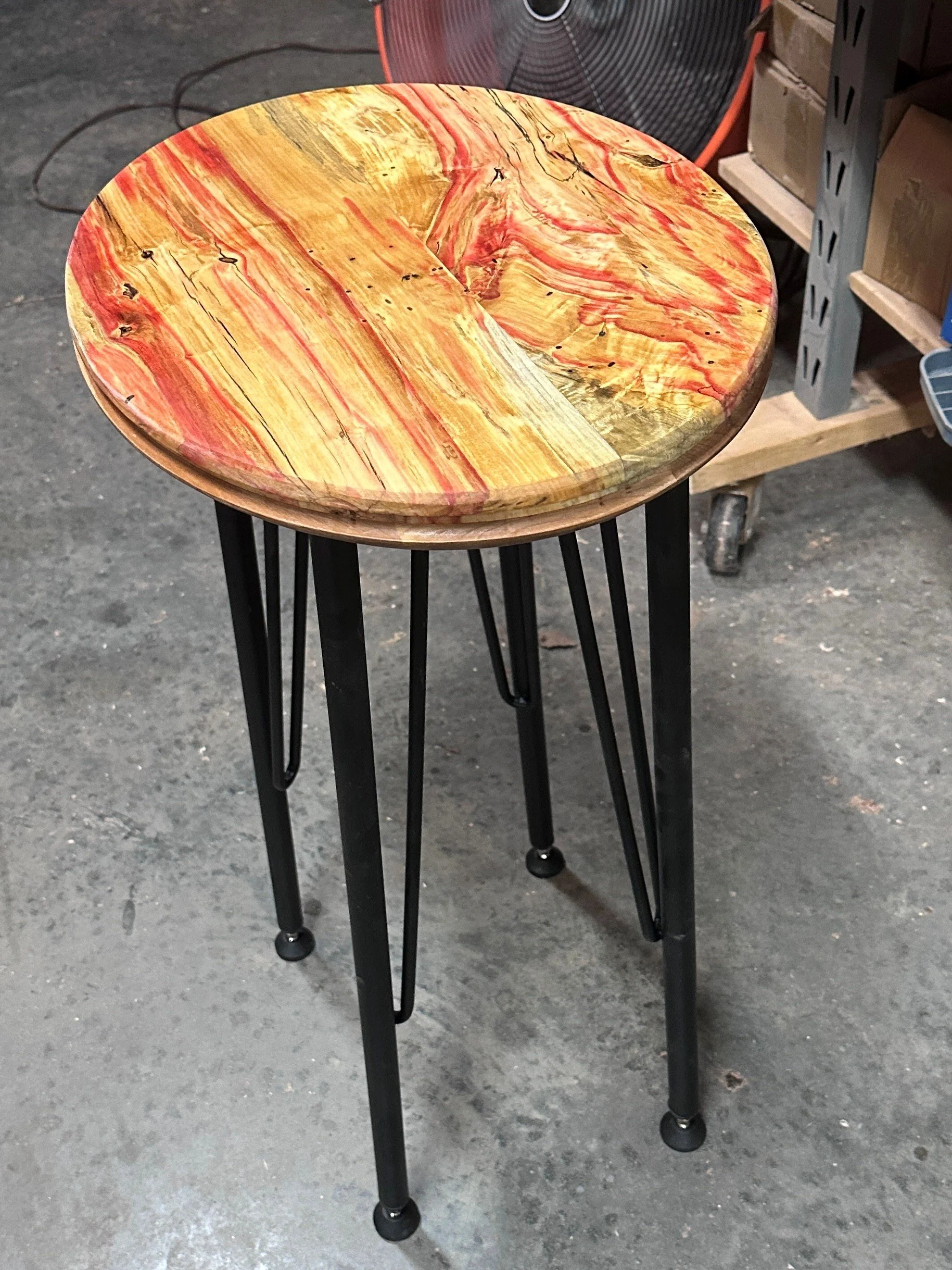 A Flaming Box Elder oval table with metal legs.
