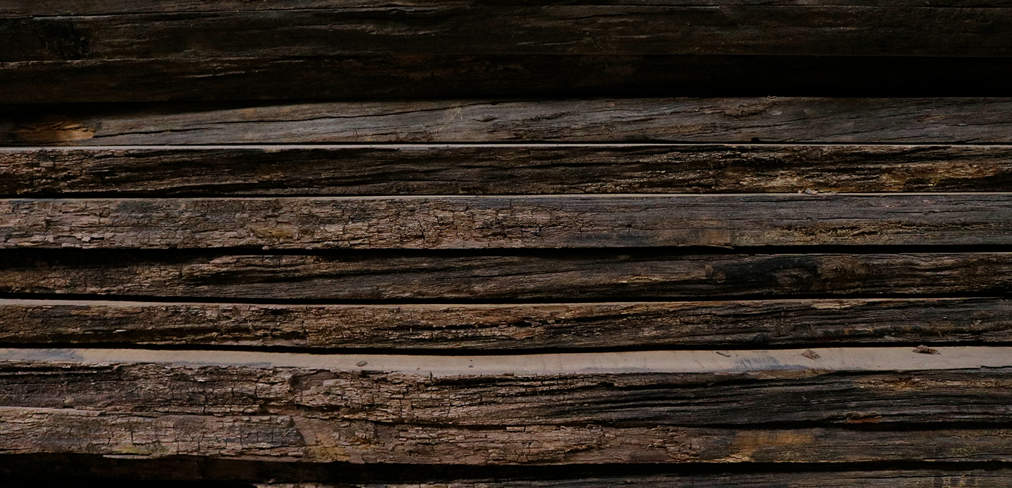 Close-up of stacked weathered wood planks with rough texture.