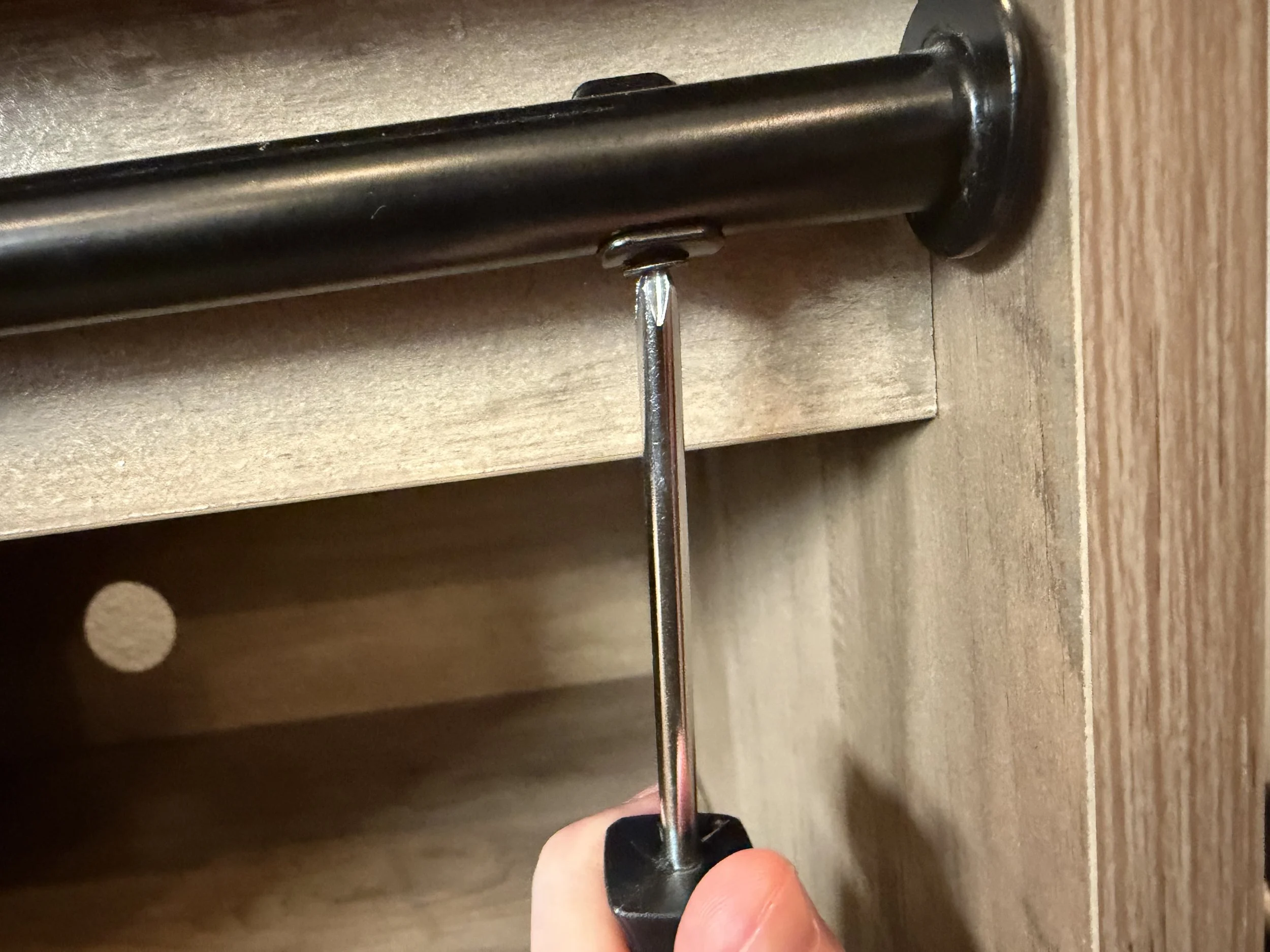 "Professional furniture assembly technician using a cordless power drill to securely install a mounting screw into a wooden furniture joint