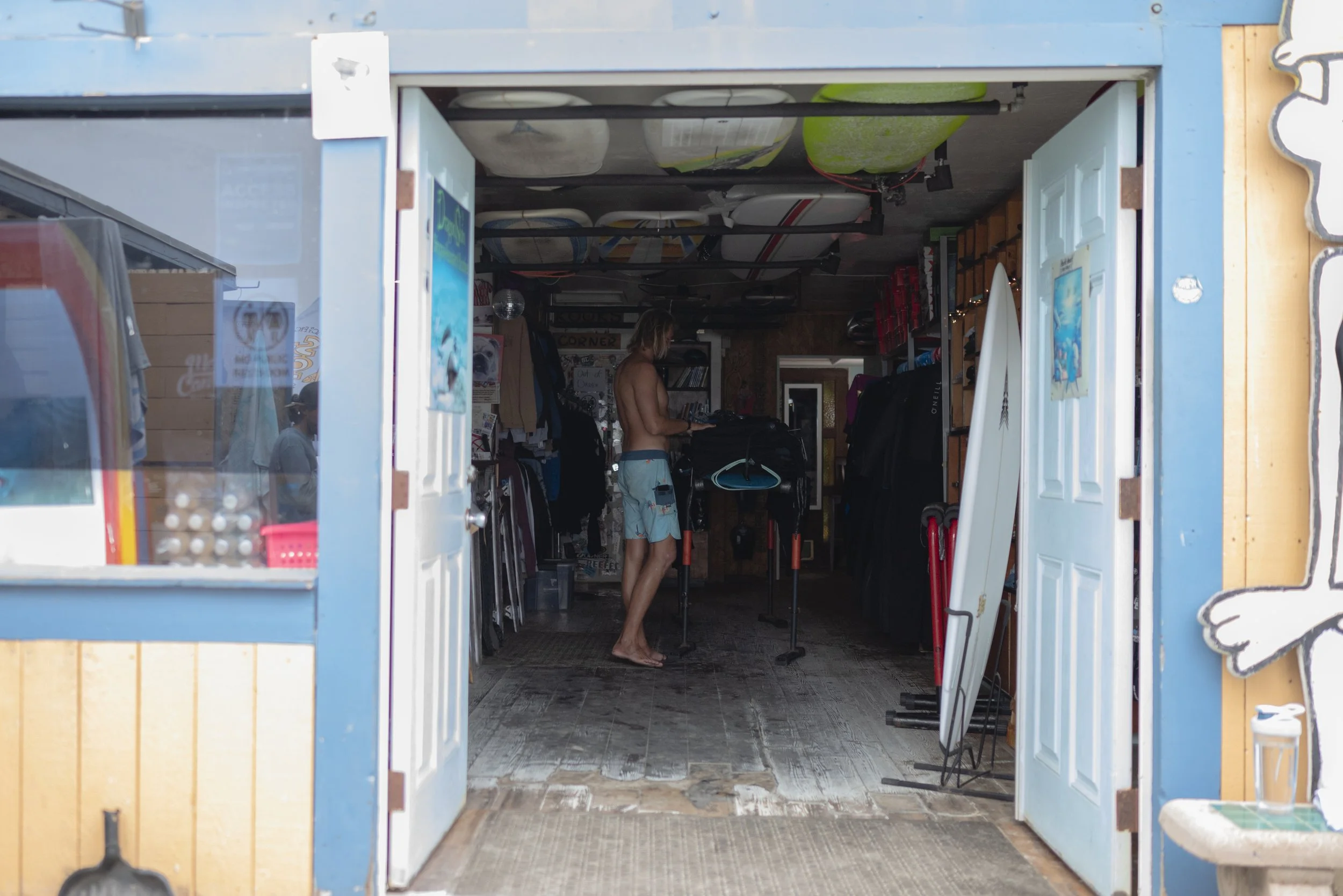 Ian Biley sorts through new wetsuit inventory at Pacific Beach Surf Shop on May 2, 2026. (For The San Diego Union-Tribune)