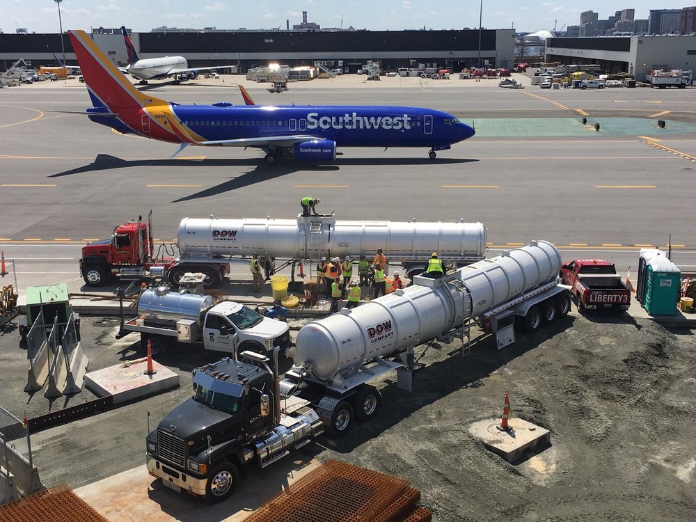Refuelling trucks with plane in background on runway
