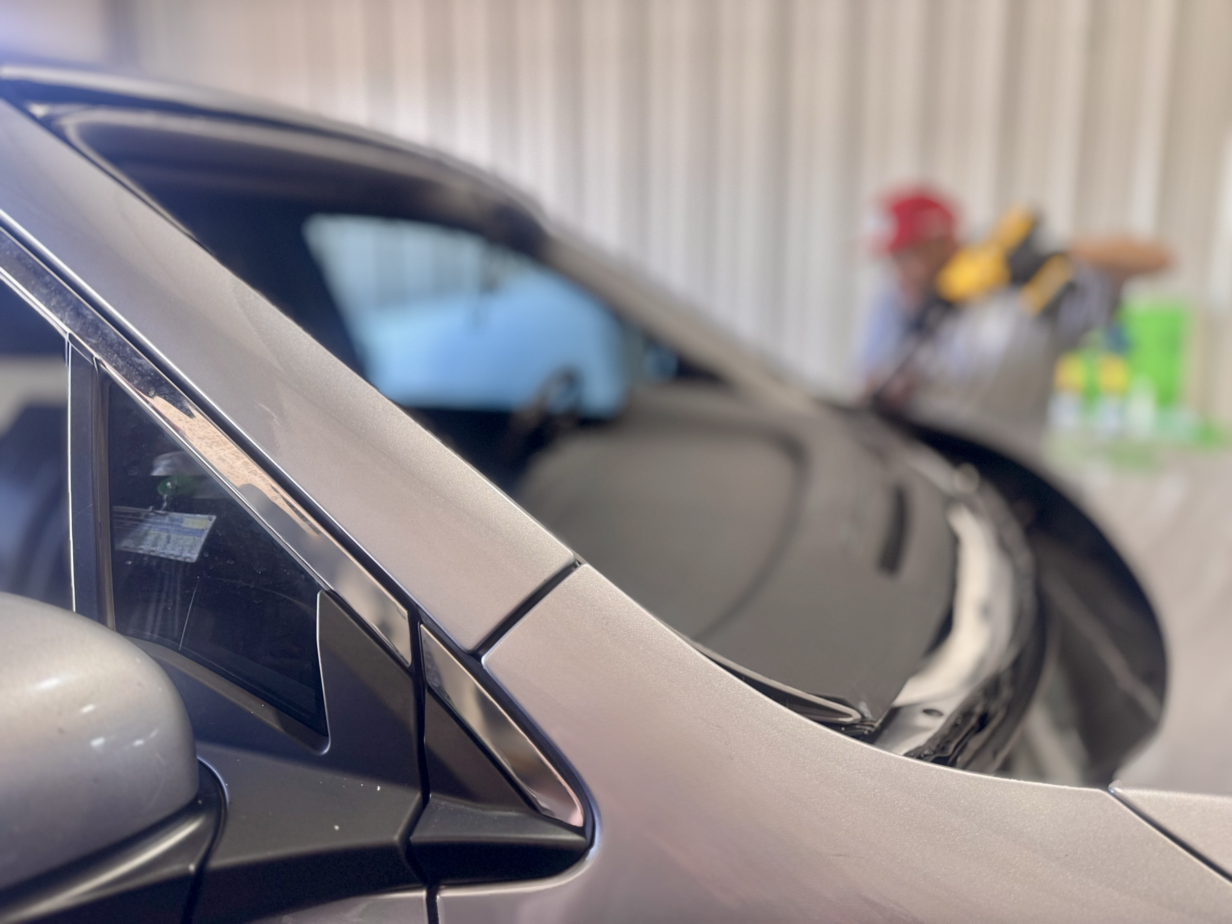 Auto glass technician at HWY 38 Glass completing windshield installation on a passenger vehicle; expert rock chip repair and windshield replacement in Northern Utah.