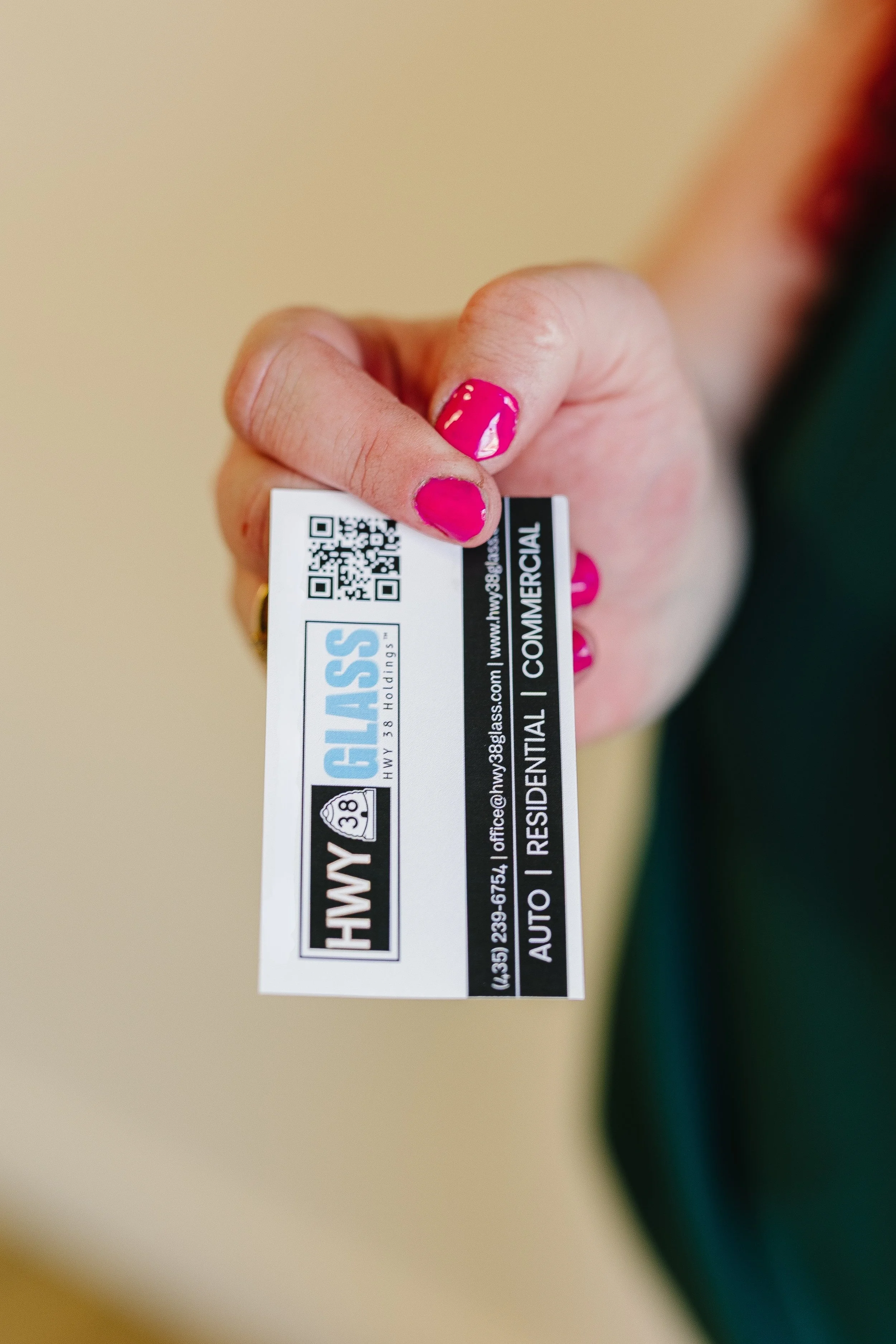 HWY 38 Glass business card held by a customer — Northern Utah residential window replacement, commercial glass, and auto glass services.”