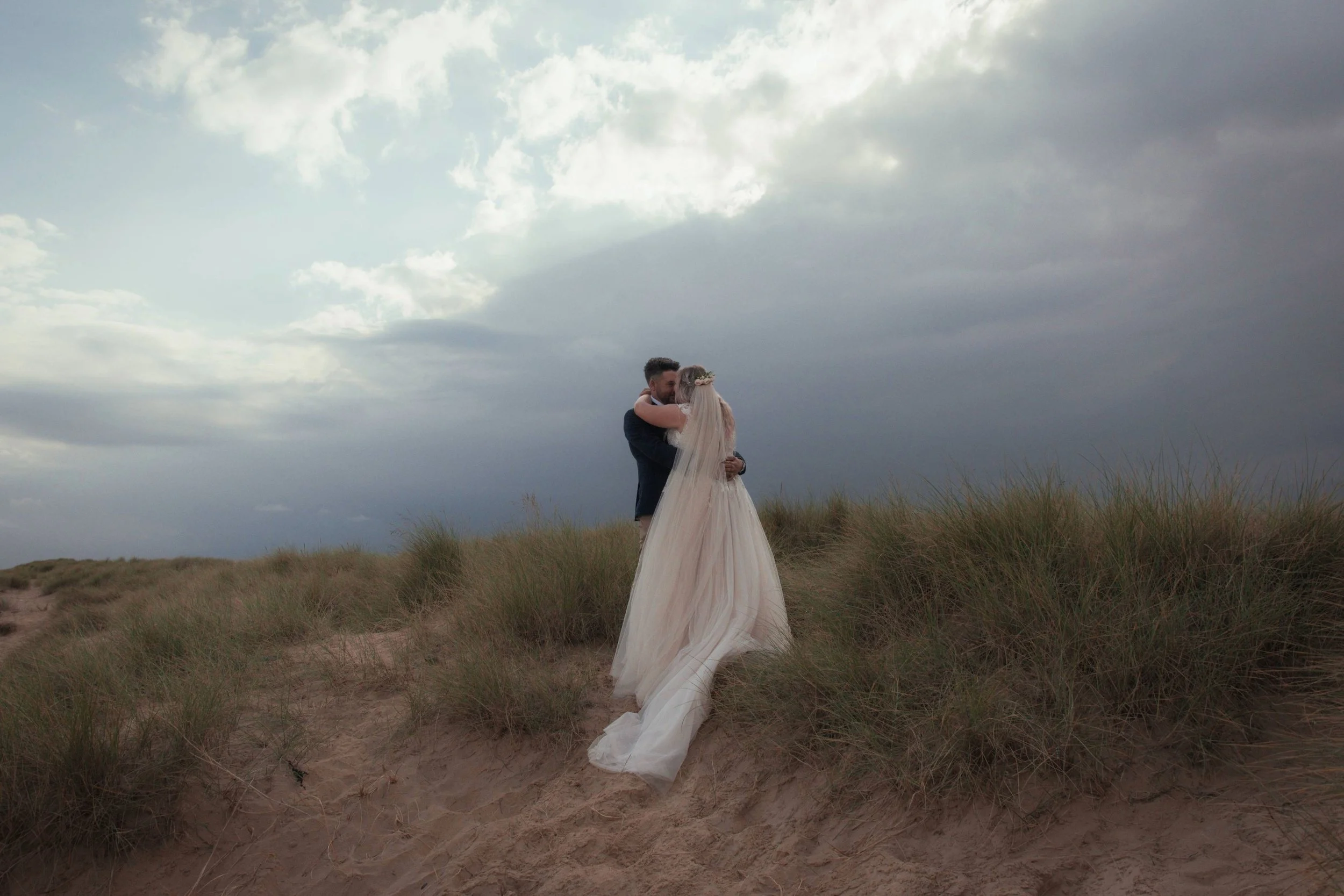 a newly married couple on a beach with a storm in the background