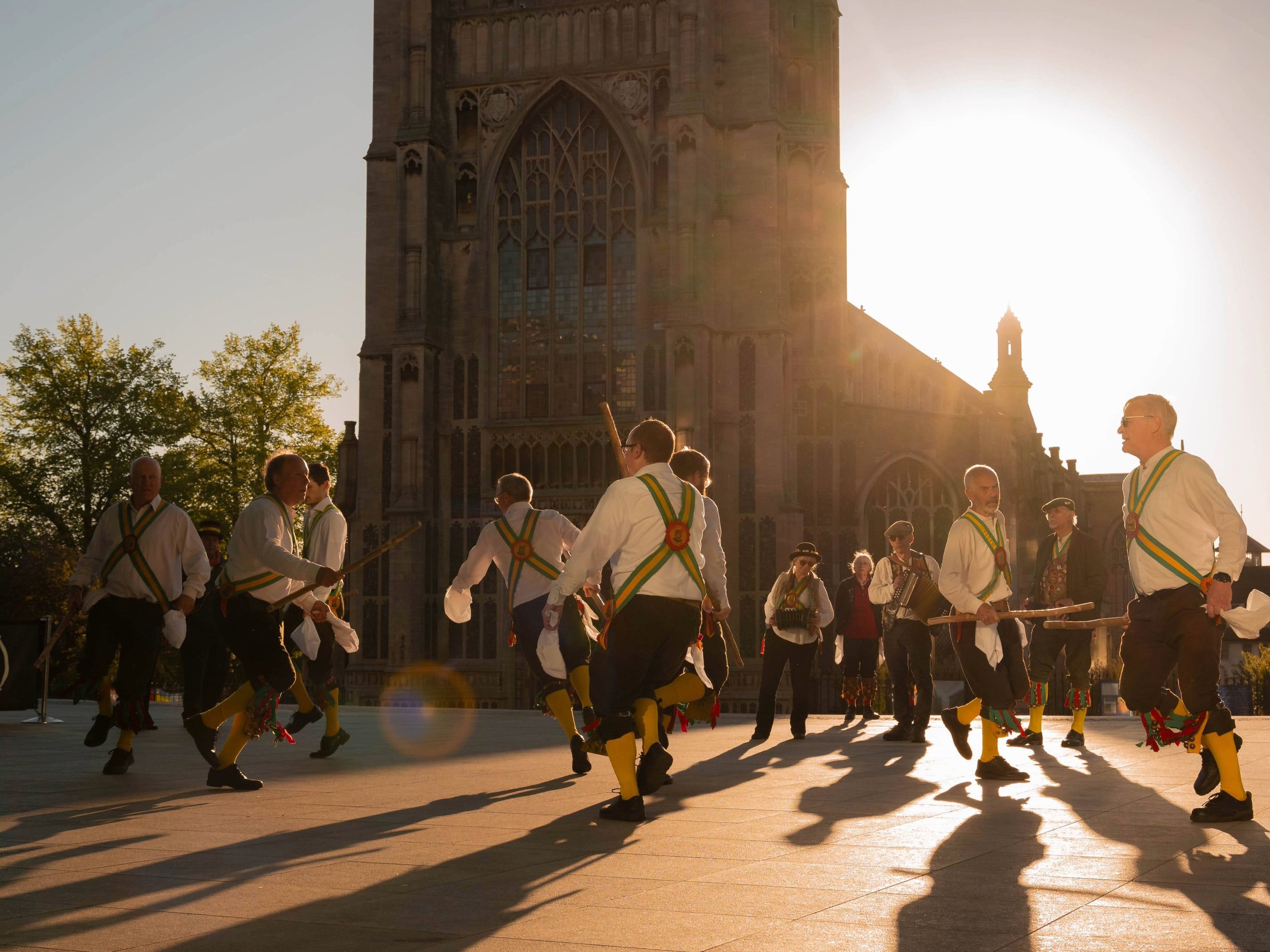a group of morris dancers infront of a church at sunrise