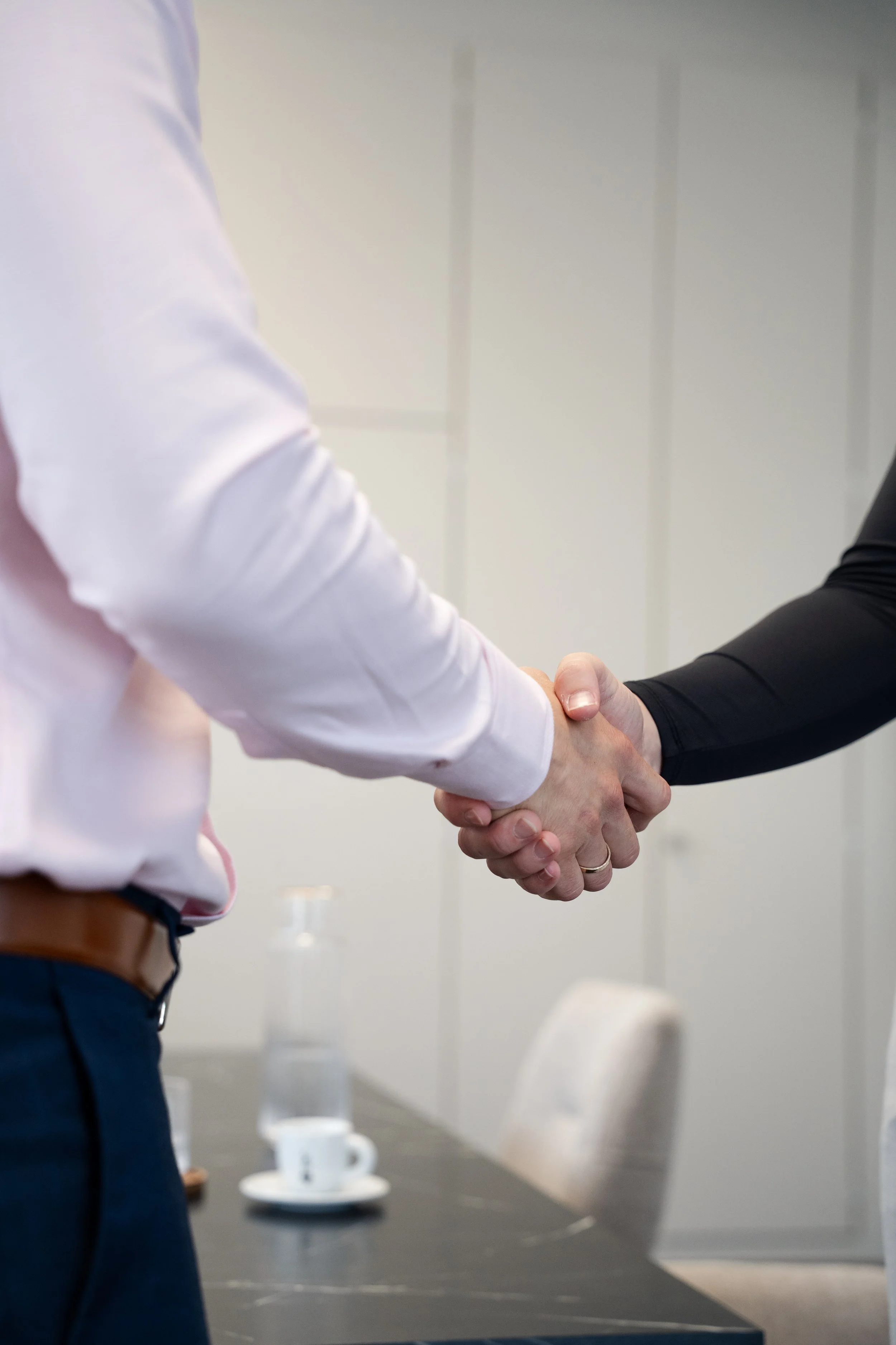 Zwei Personen schütteln sich die Hände bei einem Treffen in einem Büro.
