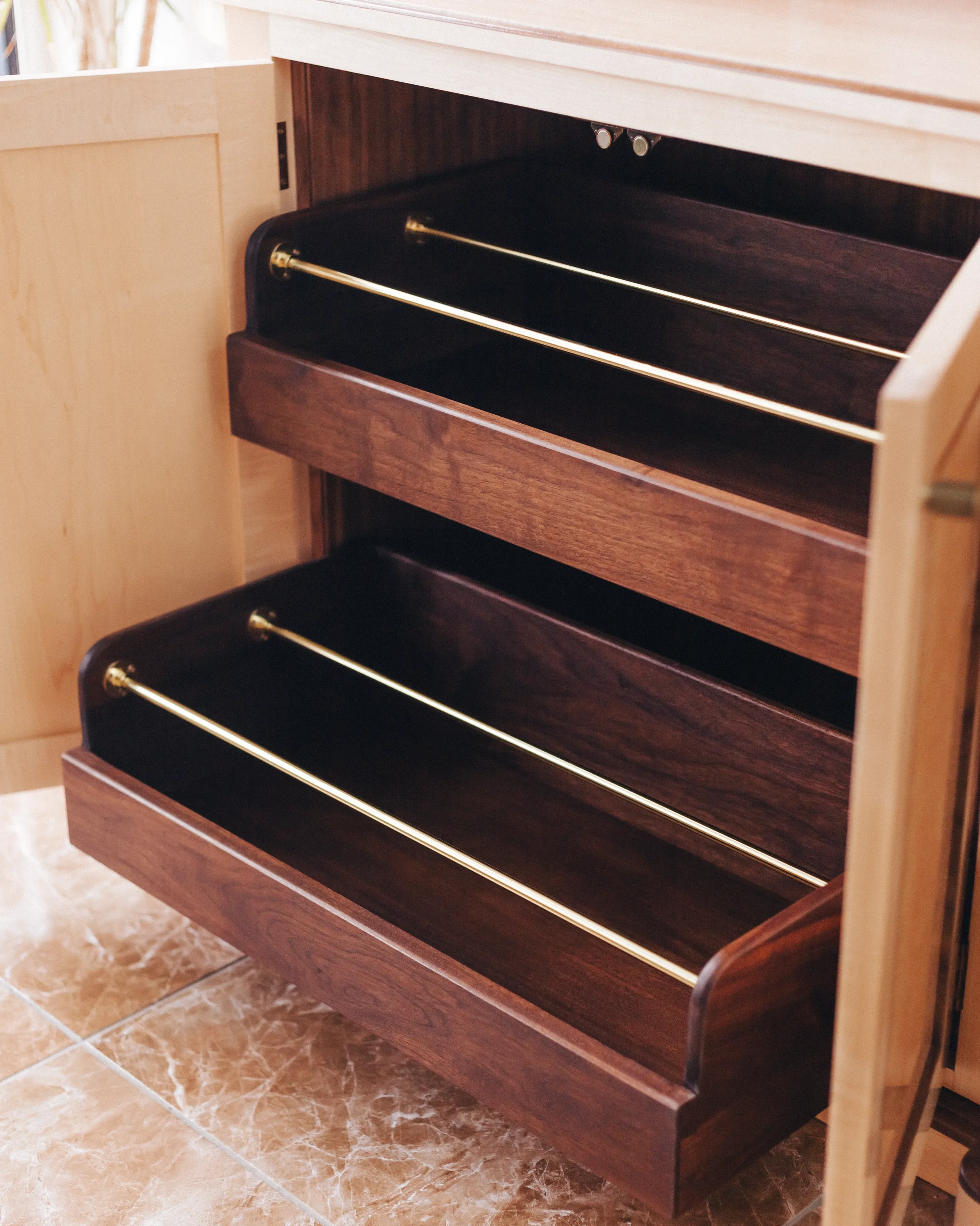 A prepared veneer Birdseye Maple and American Black Walnut shelving unit in a high gloss finish with dramatic figuring and curved shelving featuring solid Walnut shoe storage drawers with brass support rods