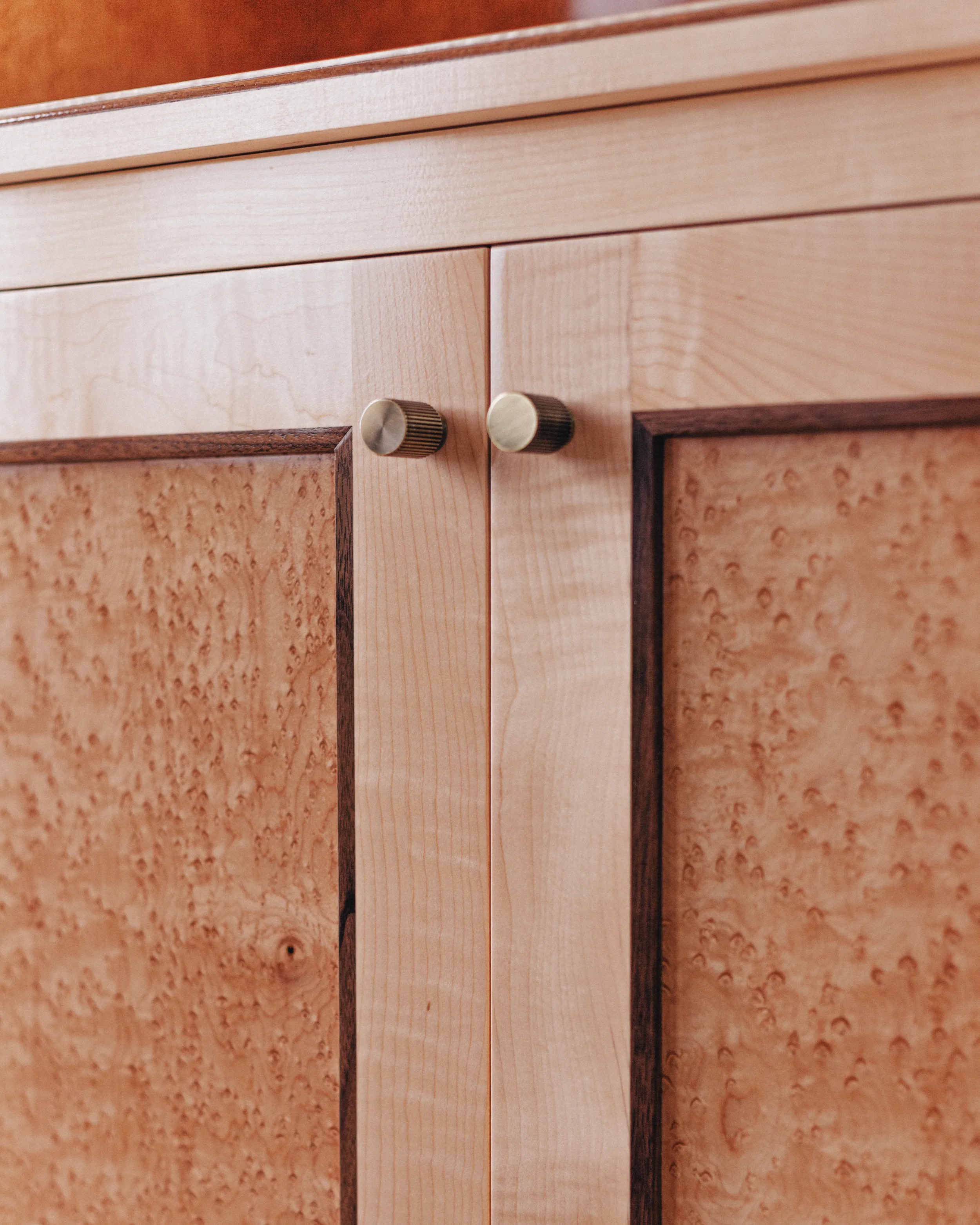 A prepared veneer Birdseye Maple and American Black Walnut shaker doors with contemporary knobs