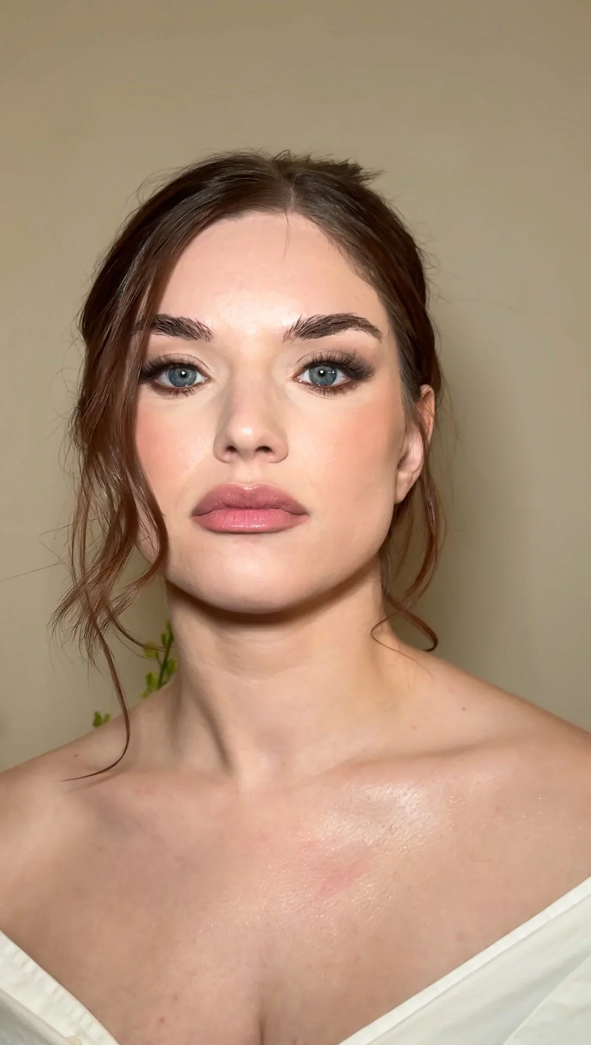 A woman with blue eyes, light makeup, and auburn hair styled in loose waves, looking directly at the camera with a neutral expression.