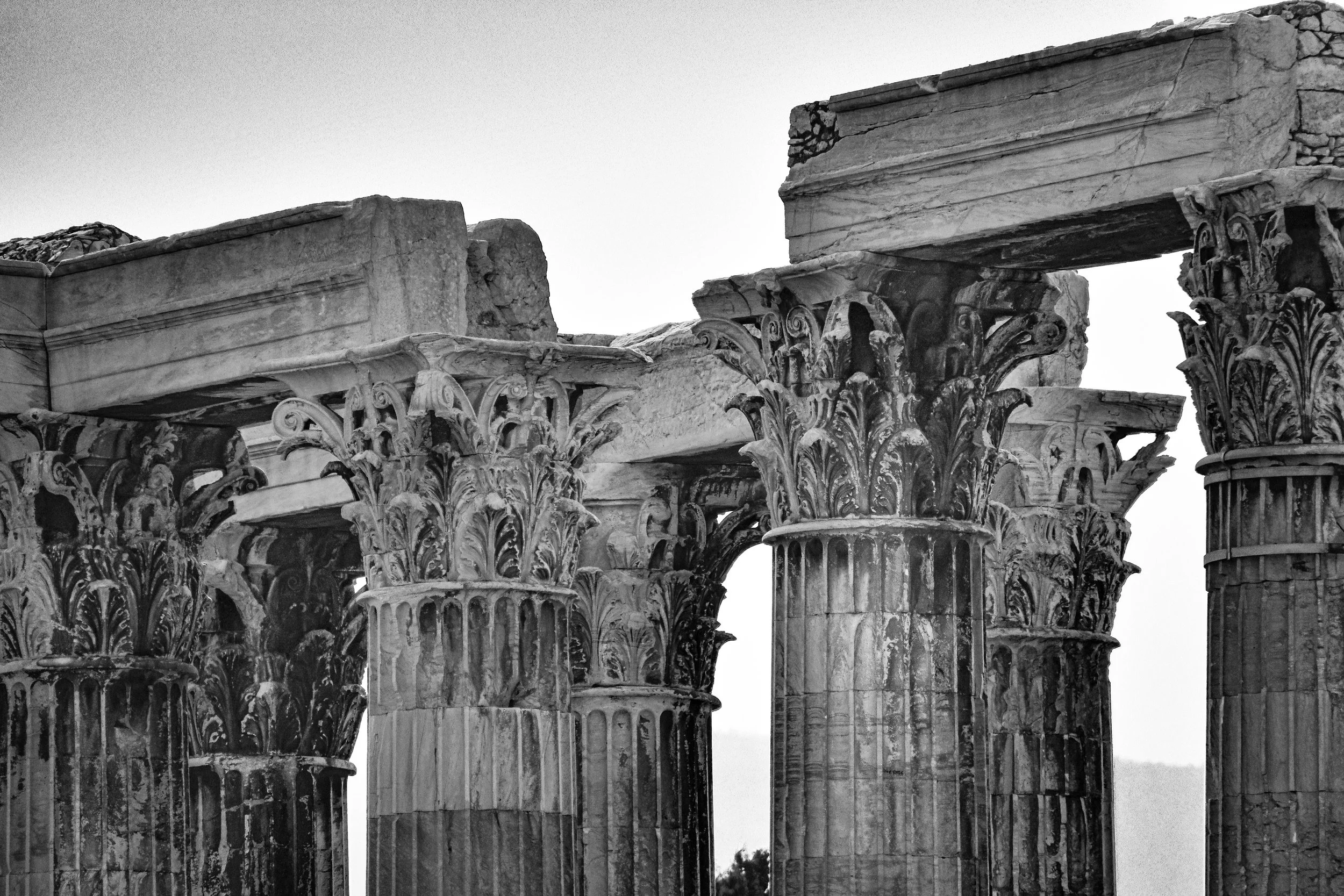 Ancient Greek ruins with weathered marble columns and architraves in grayscale.