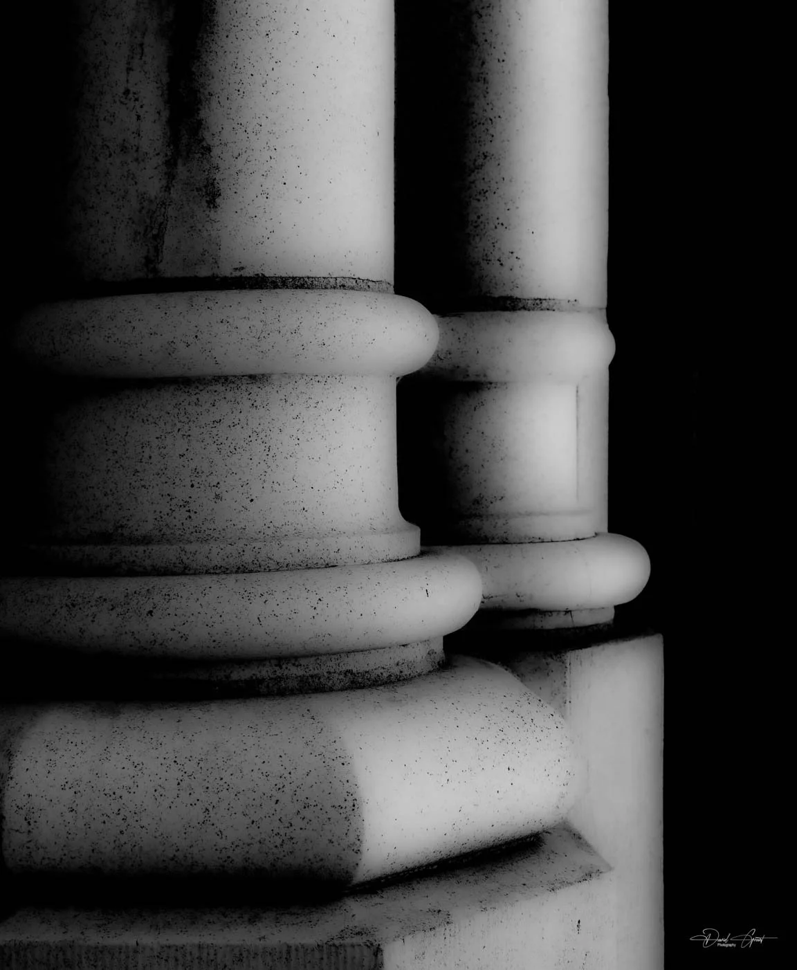 Close-up of a white marble Corinthian column with ornate details, in black and white.